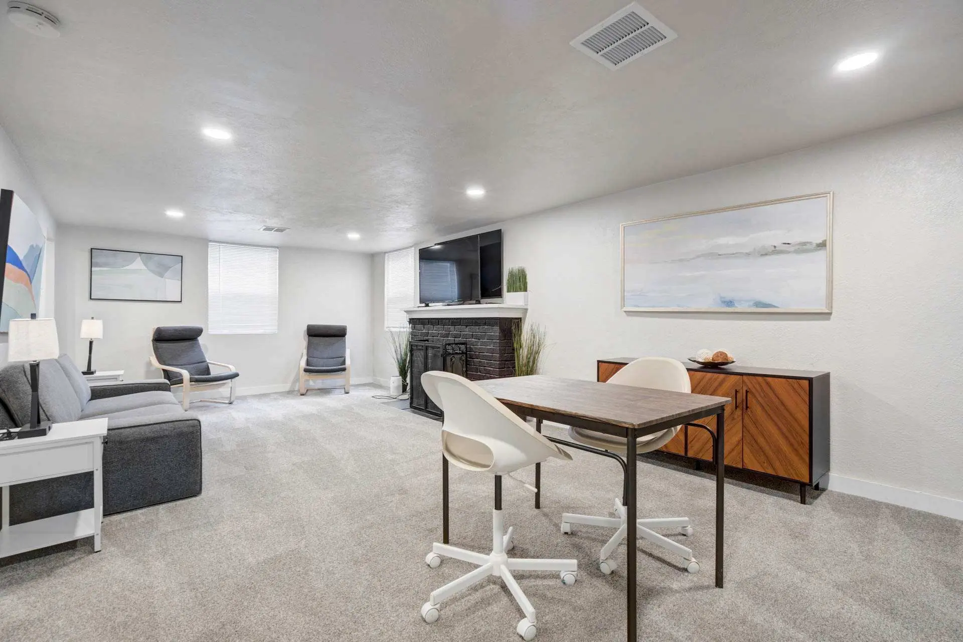 Living room with a couch, chairs, fireplace, and a desk with chairs.