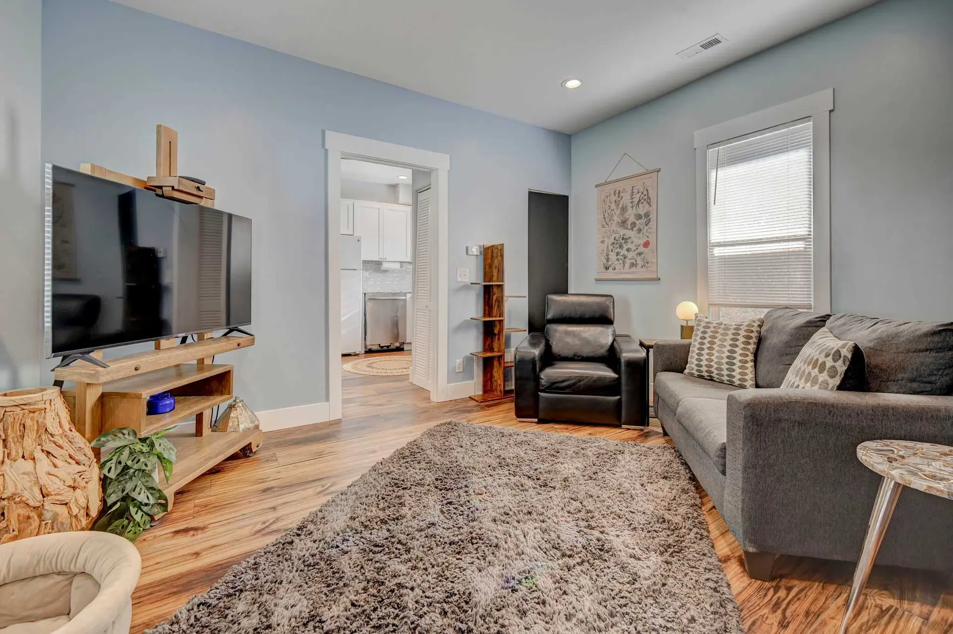 Living room with a TV, leather chair, and a grey couch on a rug.