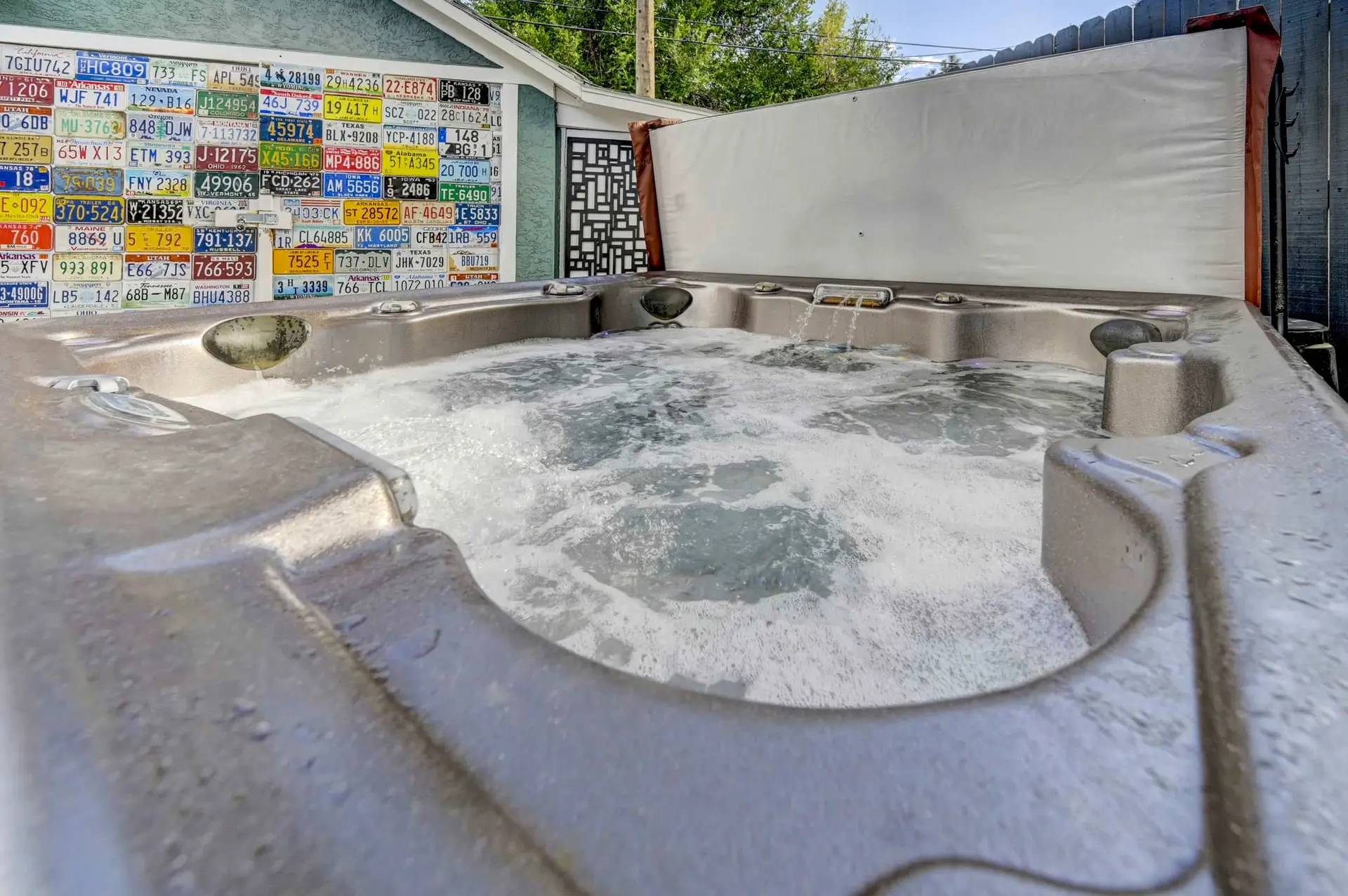 A bubbling hot tub with a wall of license plates in the background.