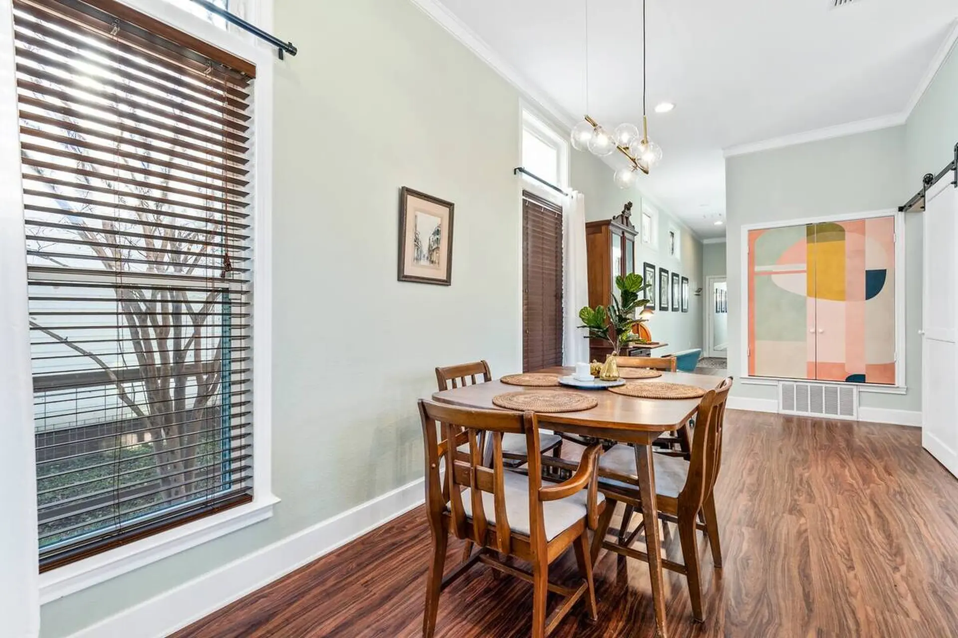 A wooden dining table and chairs are set for a meal in this dining room.
