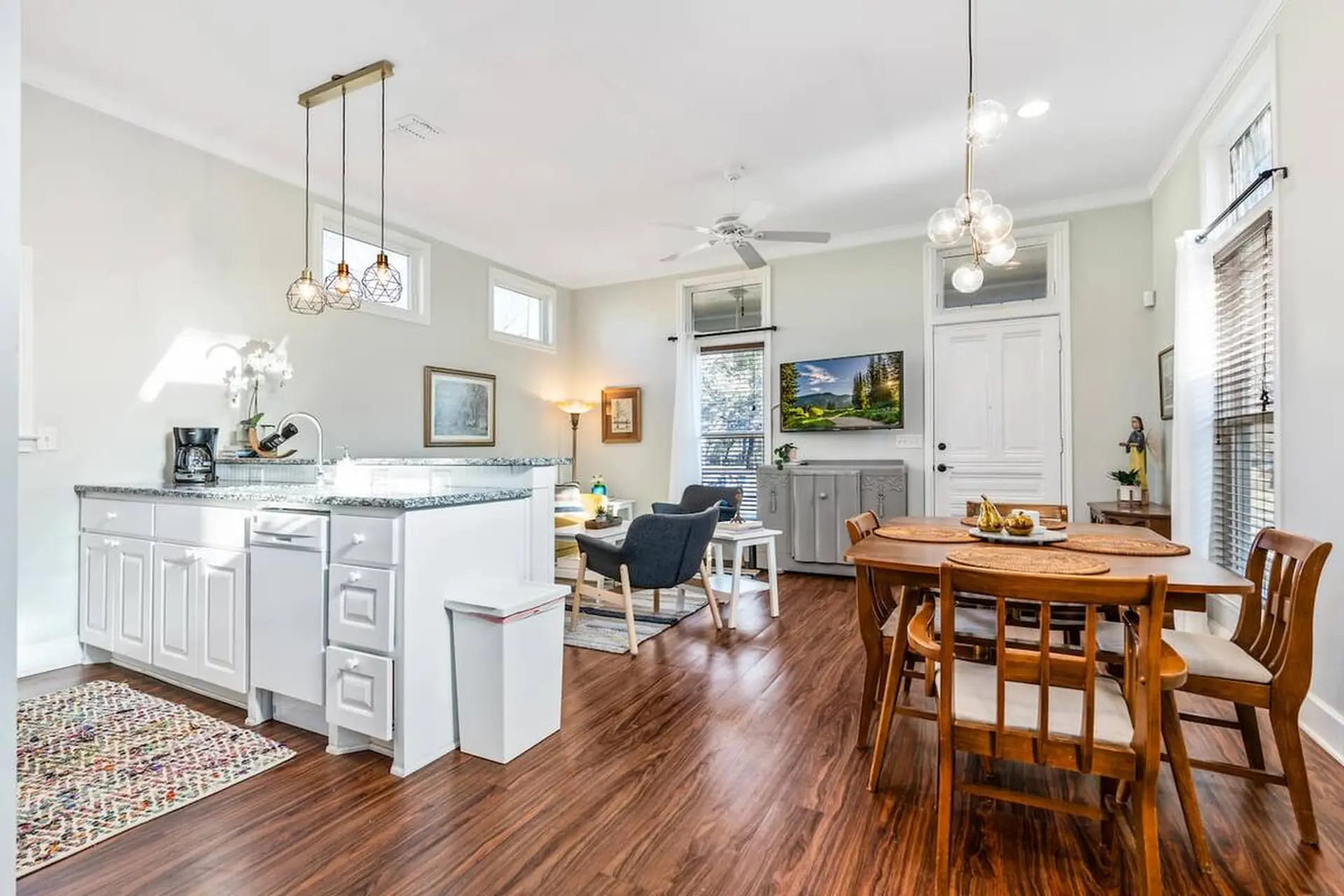 Dining room with a wooden table and chairs, and a kitchen in the background.