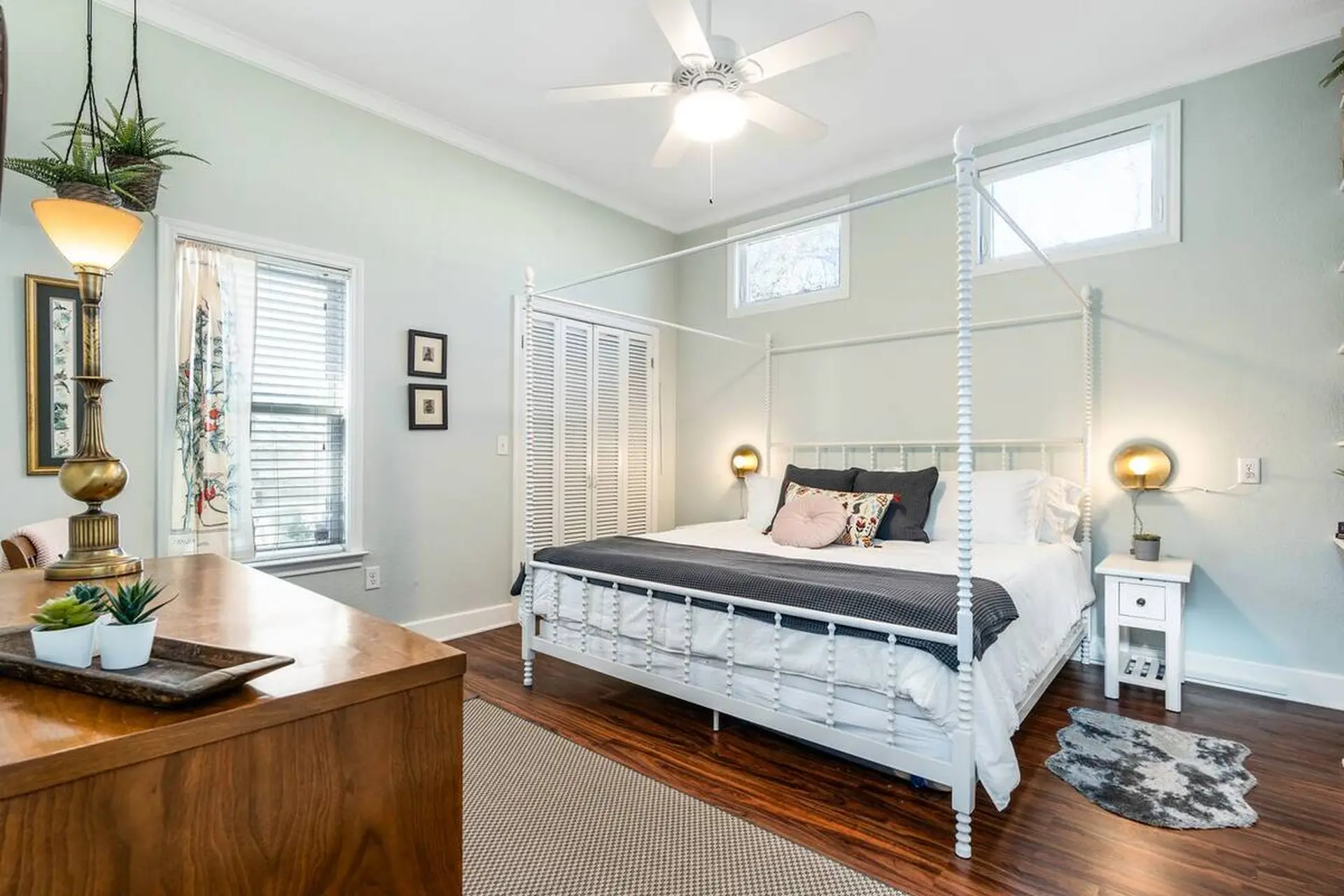 A bedroom with a canopy bed, dresser, and plants.