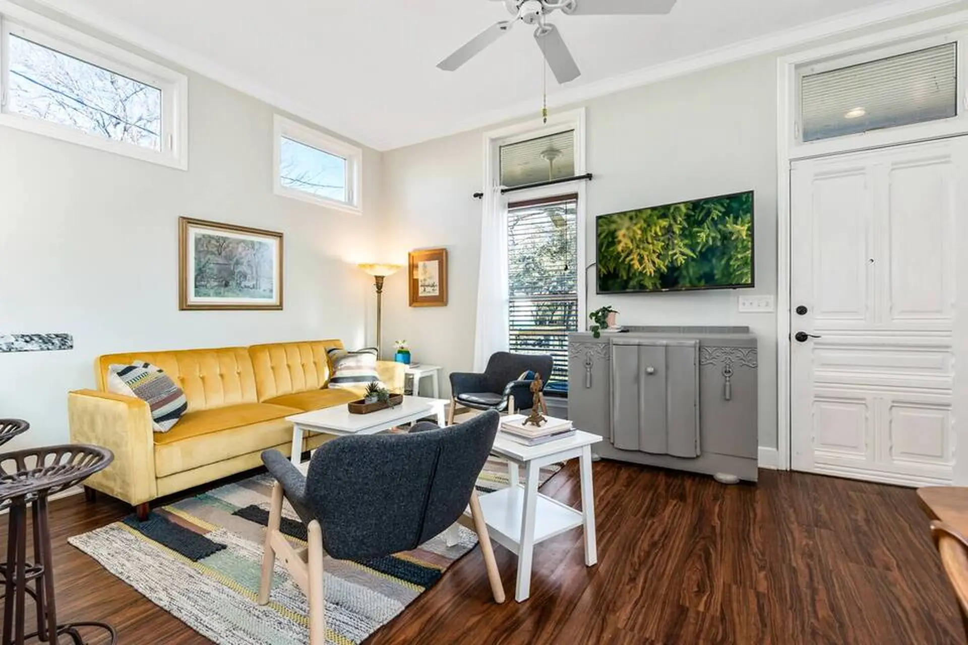 Living room with yellow couch, grey chairs, and TV.