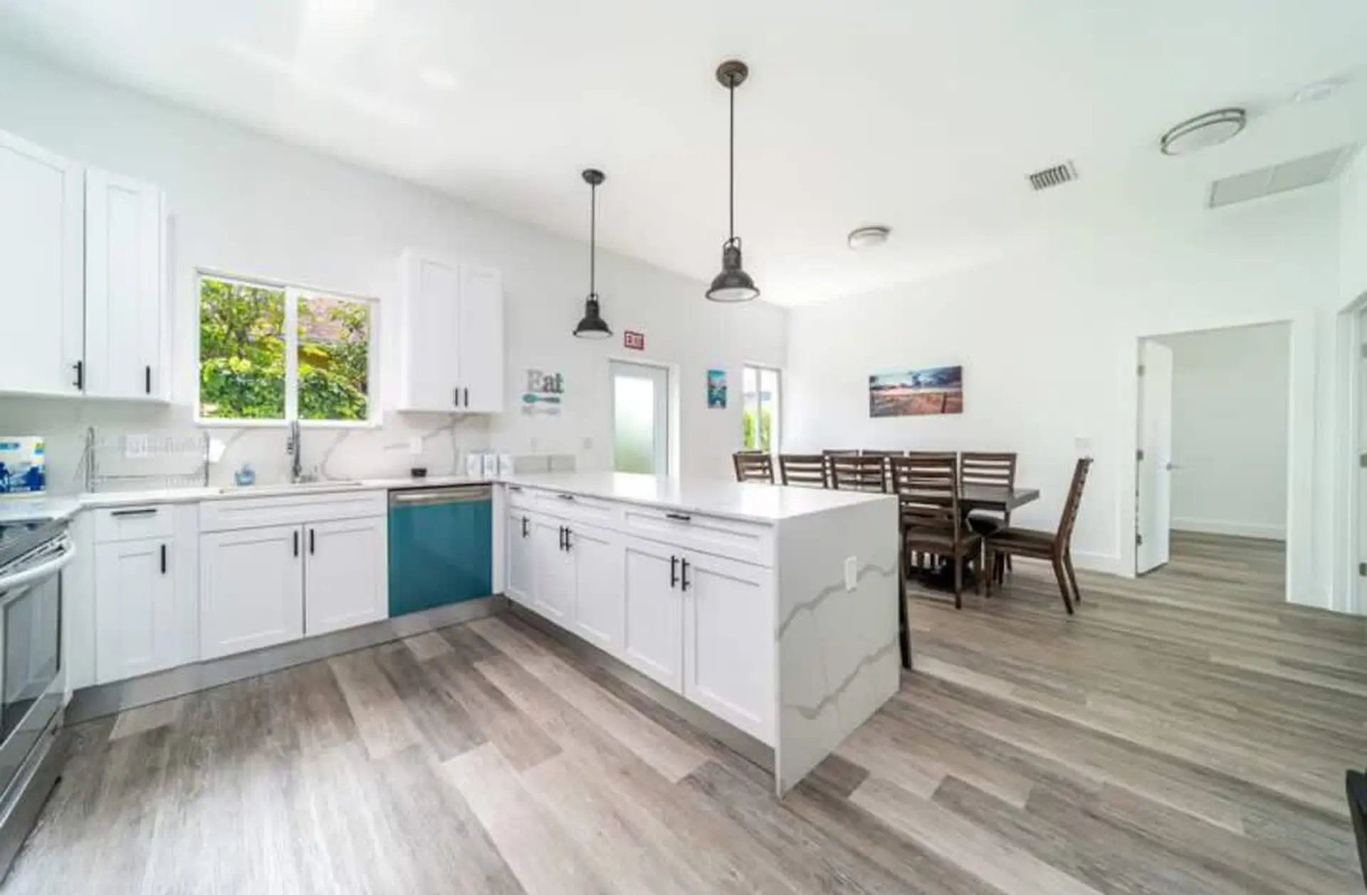 Modern kitchen and dining area with white cabinets, island, and wooden dining table.