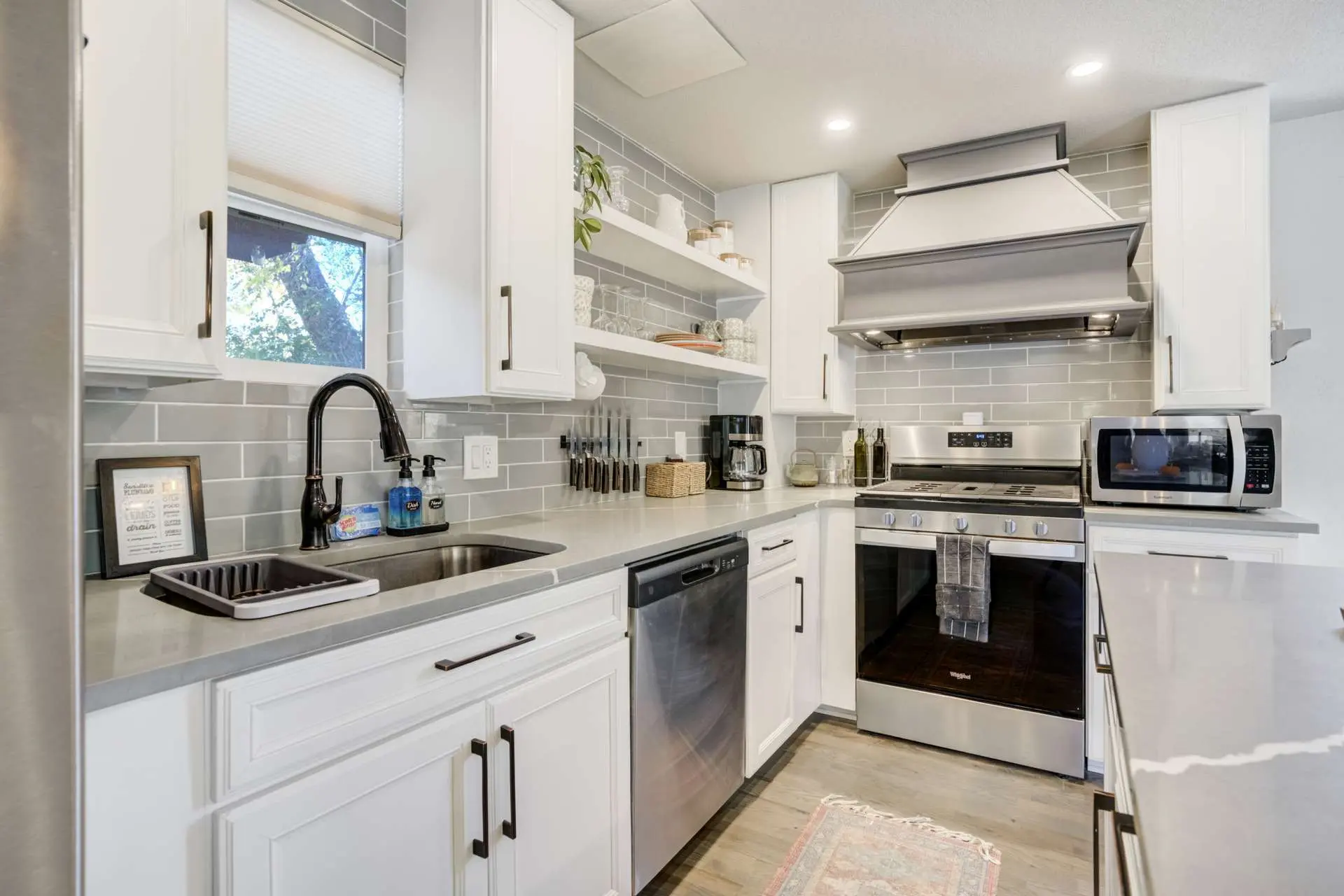 Modern kitchen with stainless steel appliances, white cabinets, and gray tile backsplash.
