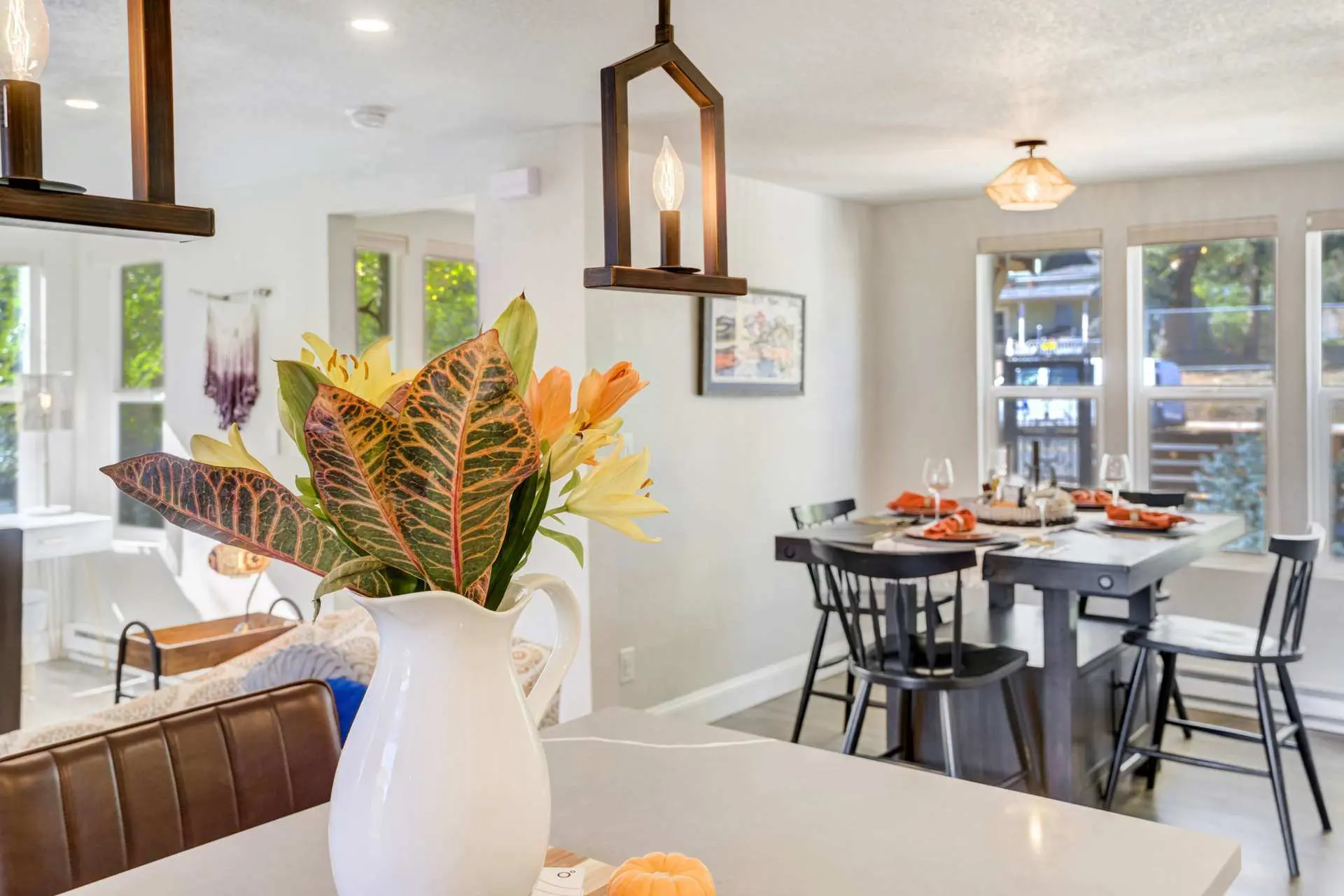 A vase of colorful flowers sits on a kitchen counter, with a dining table and chairs in the backgrou