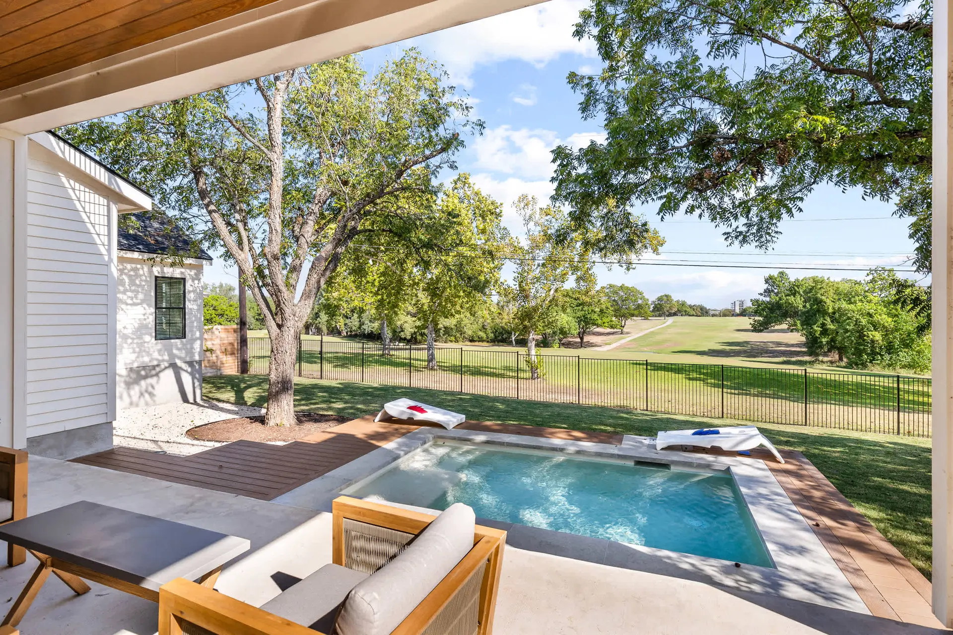 A modern patio with a small pool overlooks a golf course.