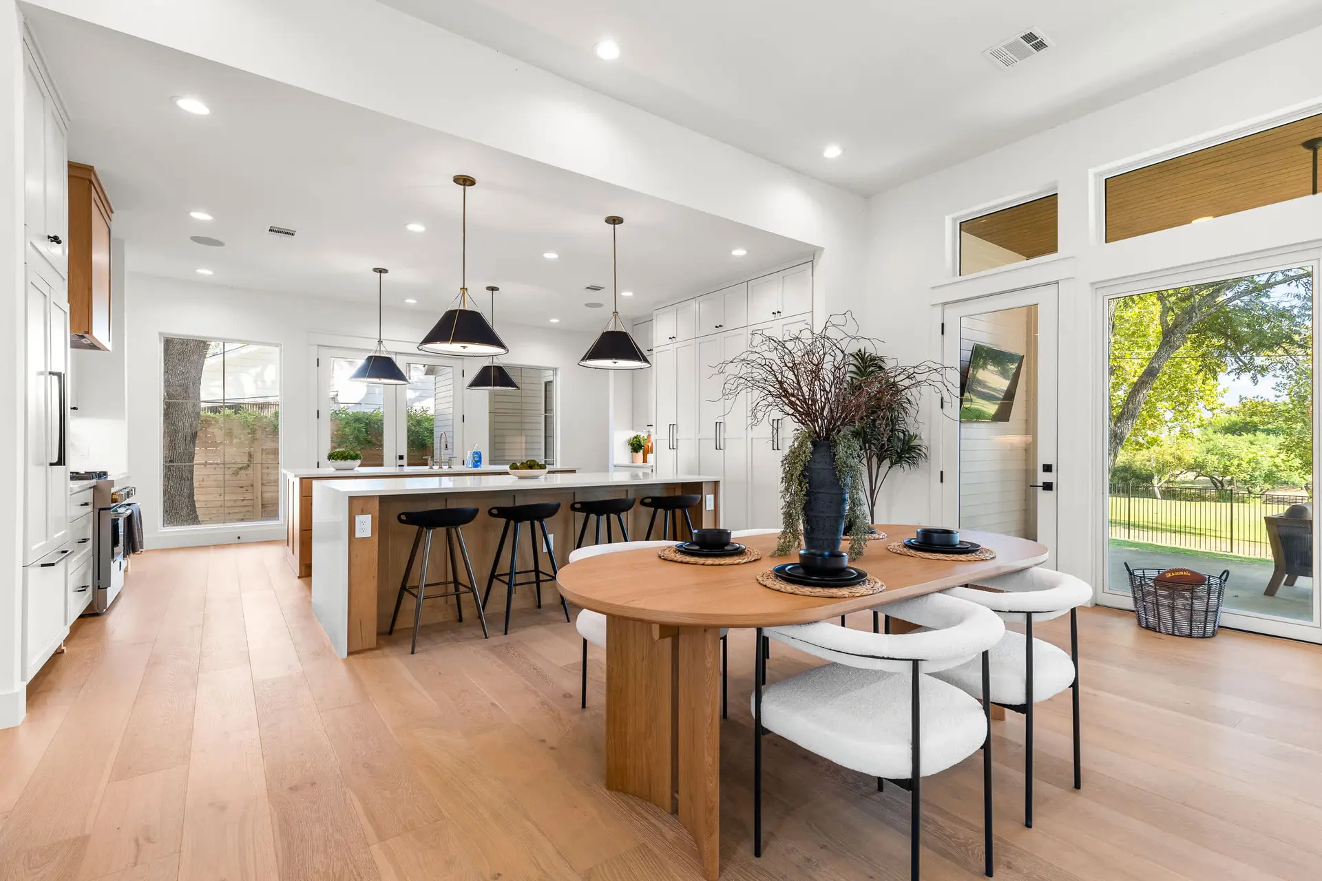 A modern open-concept kitchen and dining area with white cabinets, a large island, and an oval dinin