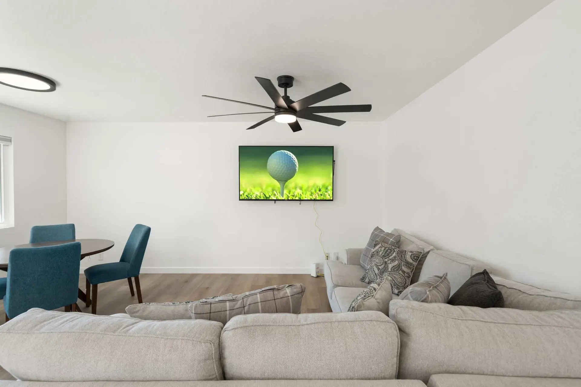 A modern living room with a sectional sofa, television, and dining area.
