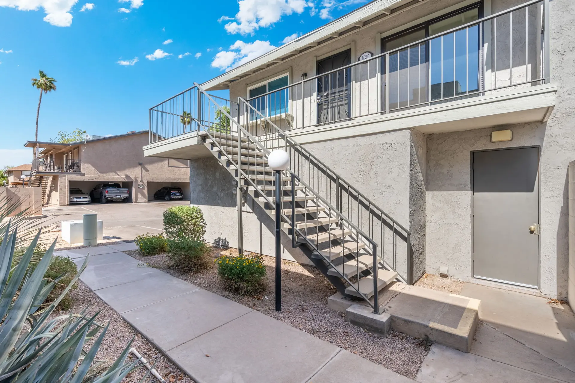 Exterior view of a stucco apartment building with an outdoor staircase leading to the second floor.