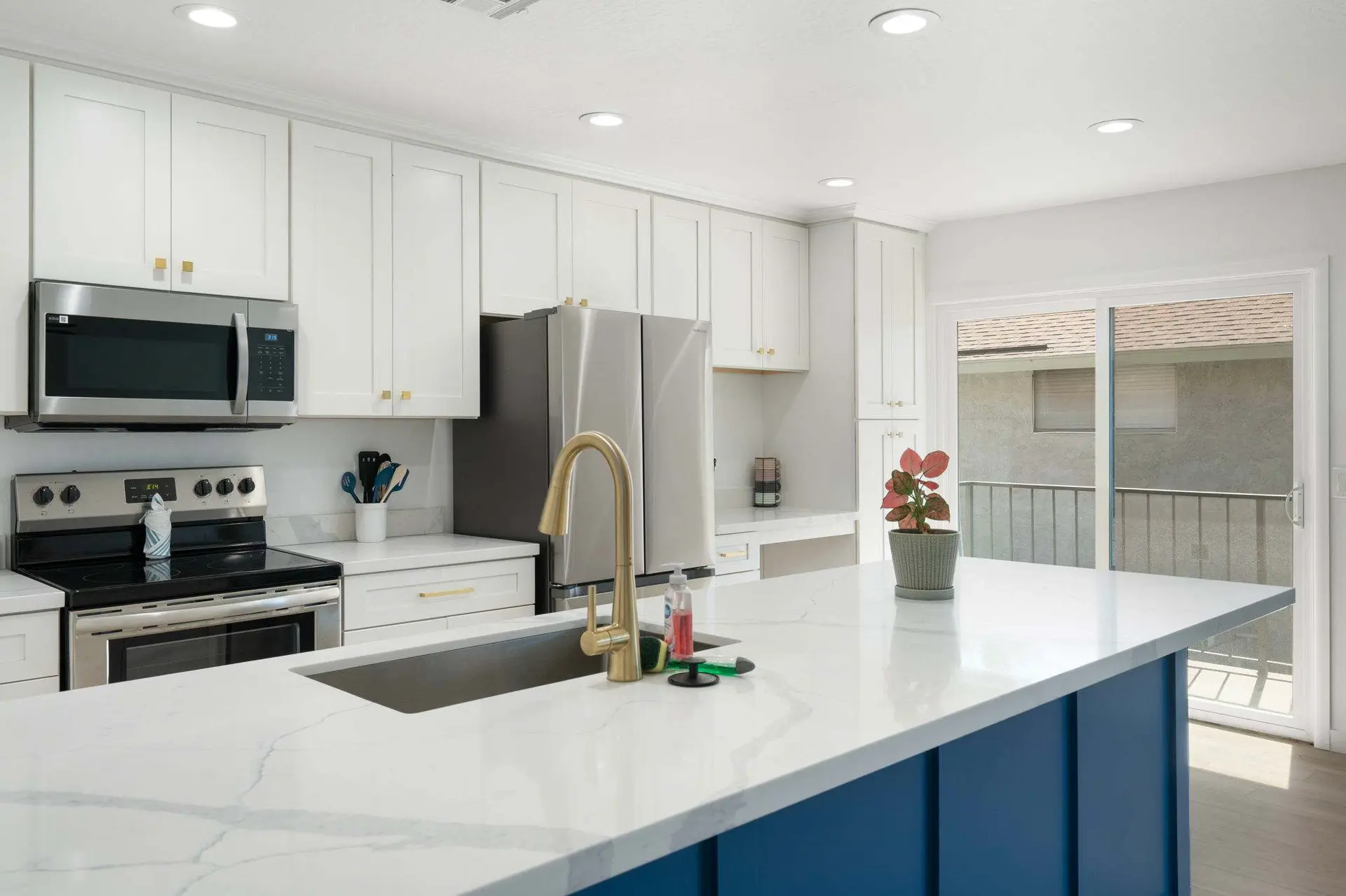 A modern kitchen with white cabinets, a stainless steel refrigerator, and a blue island with a white