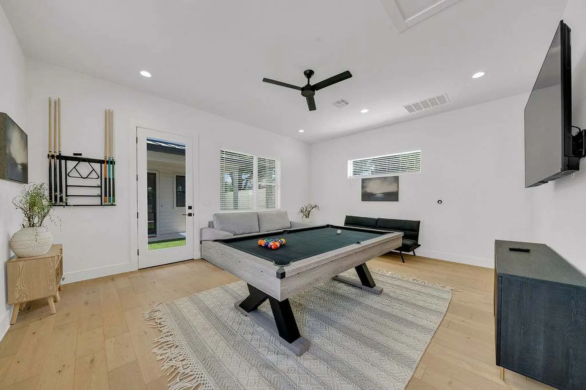 A modern game room with a pool table, sofa, and TV.
