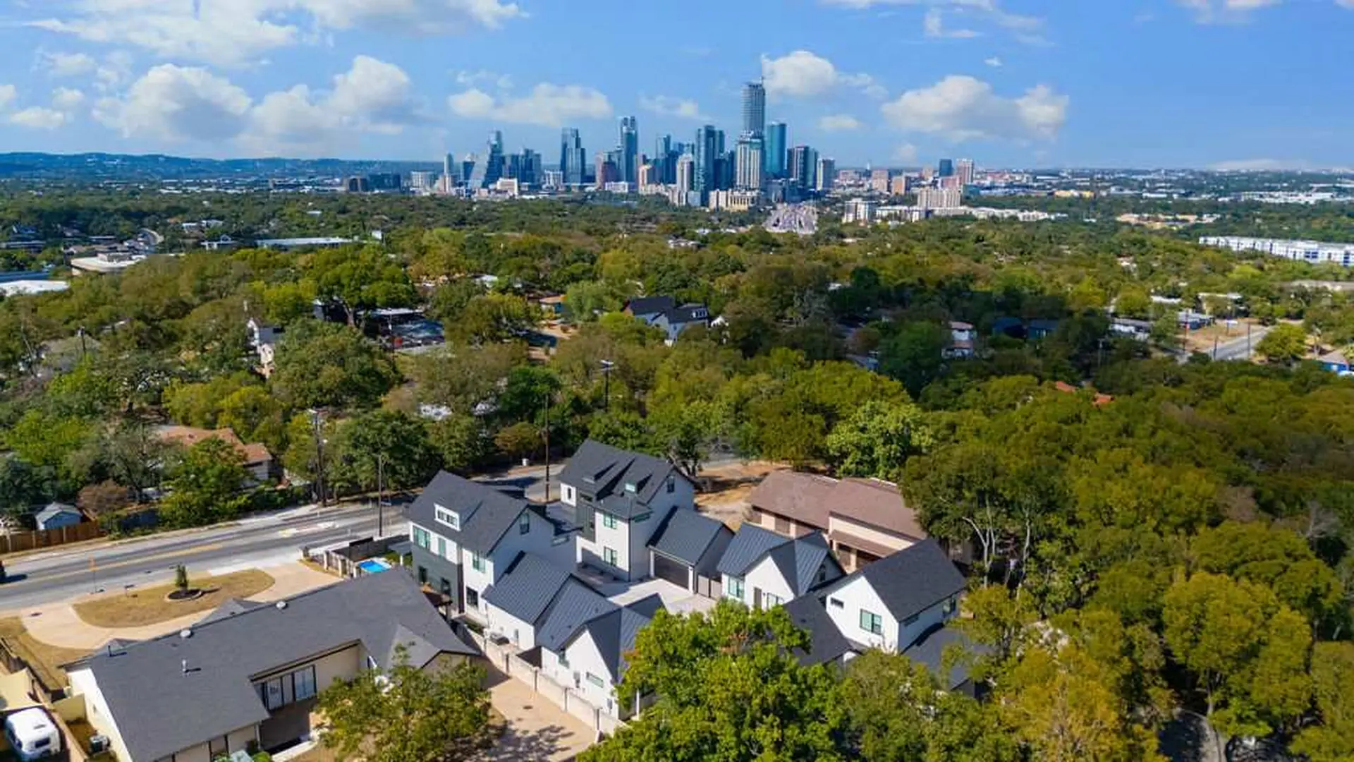 An aerial view of a suburban neighborhood with a city skyline in the distance.
