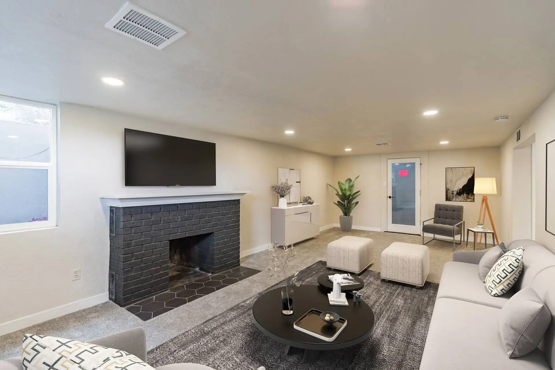 A large black television is mounted on the wall above a charcoal-colored brick fireplace.