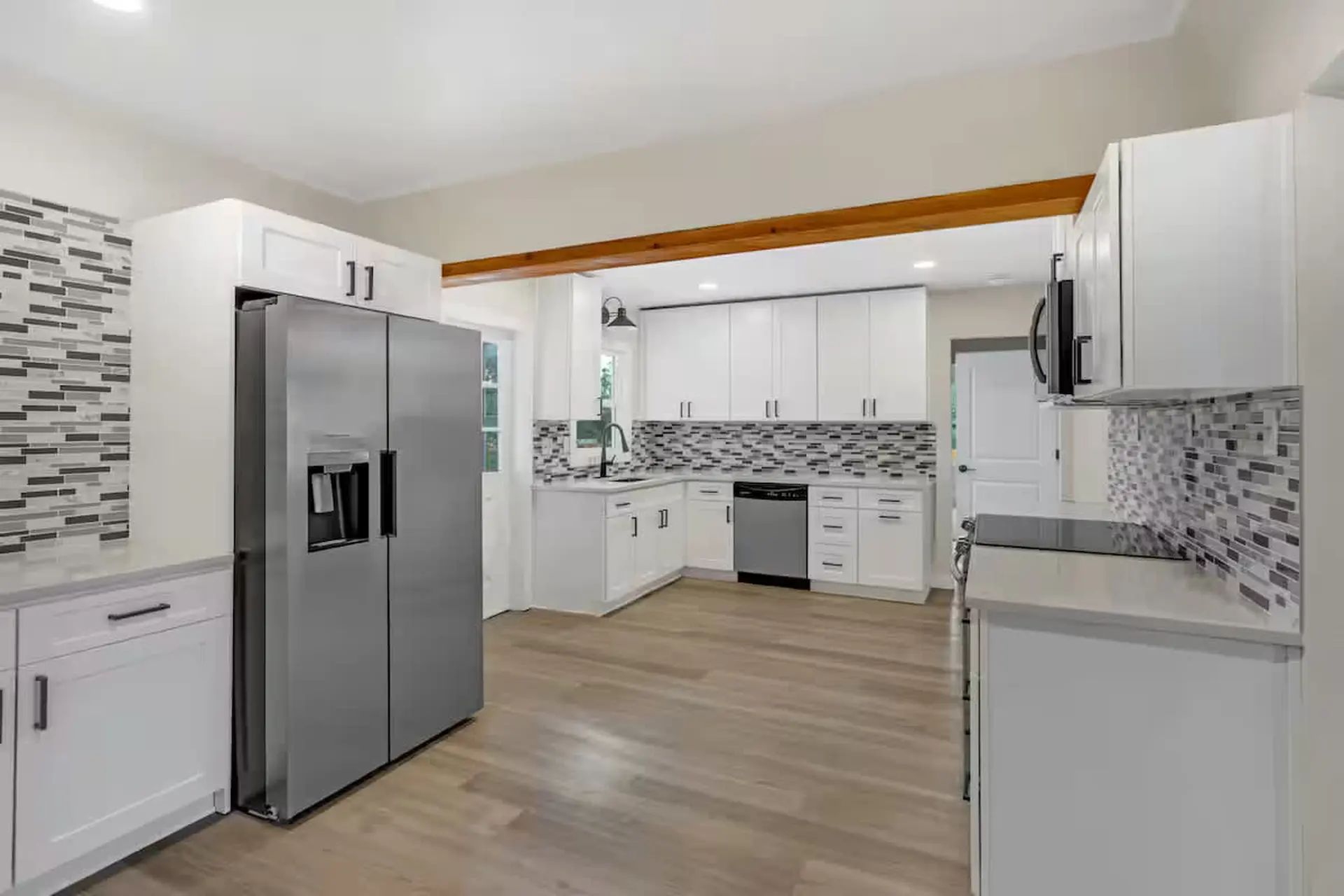 A modern kitchen with white cabinets, stainless steel appliances, and a tile backsplash.