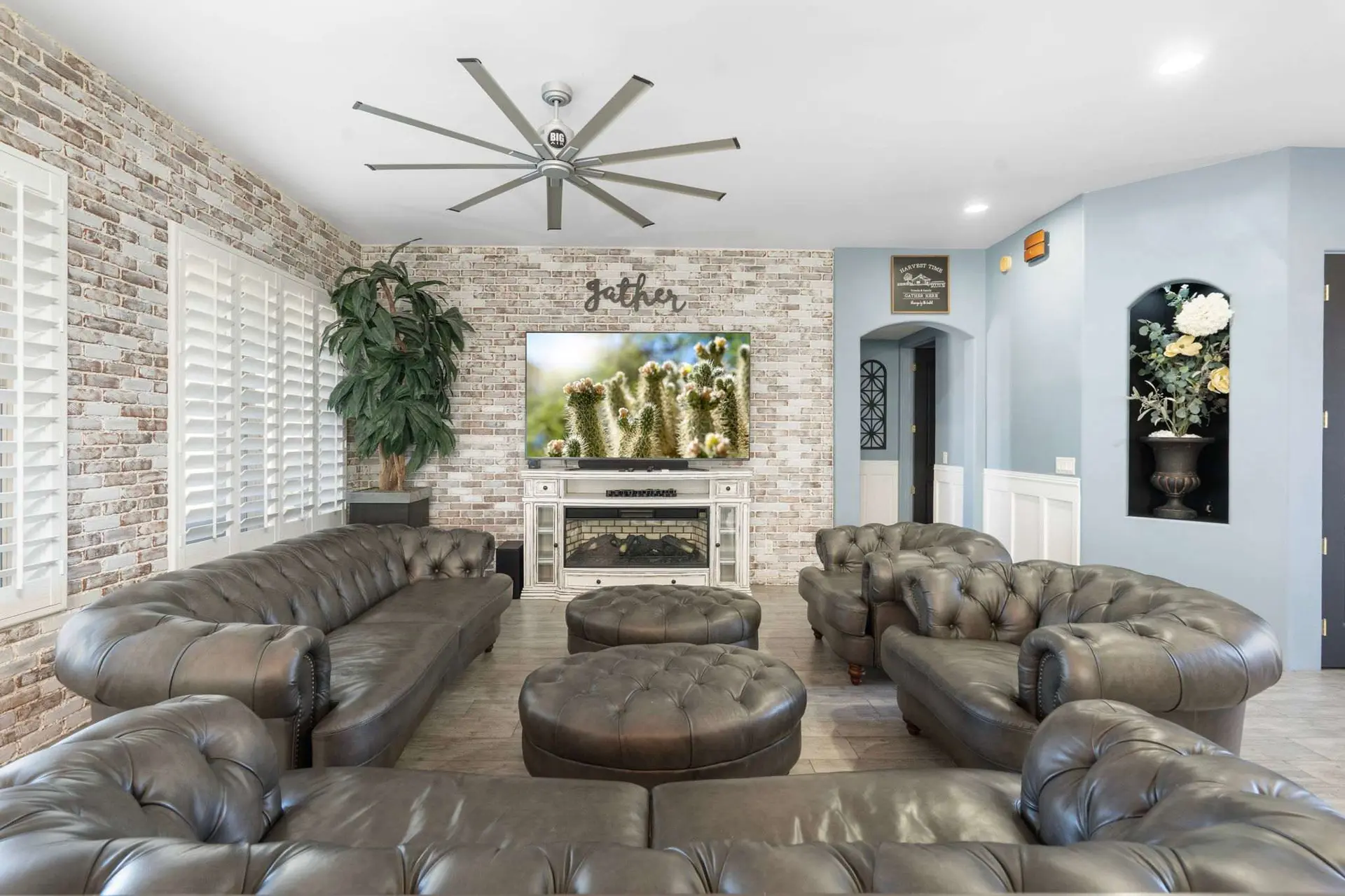 A living room with a brick wall, couches, and a TV.