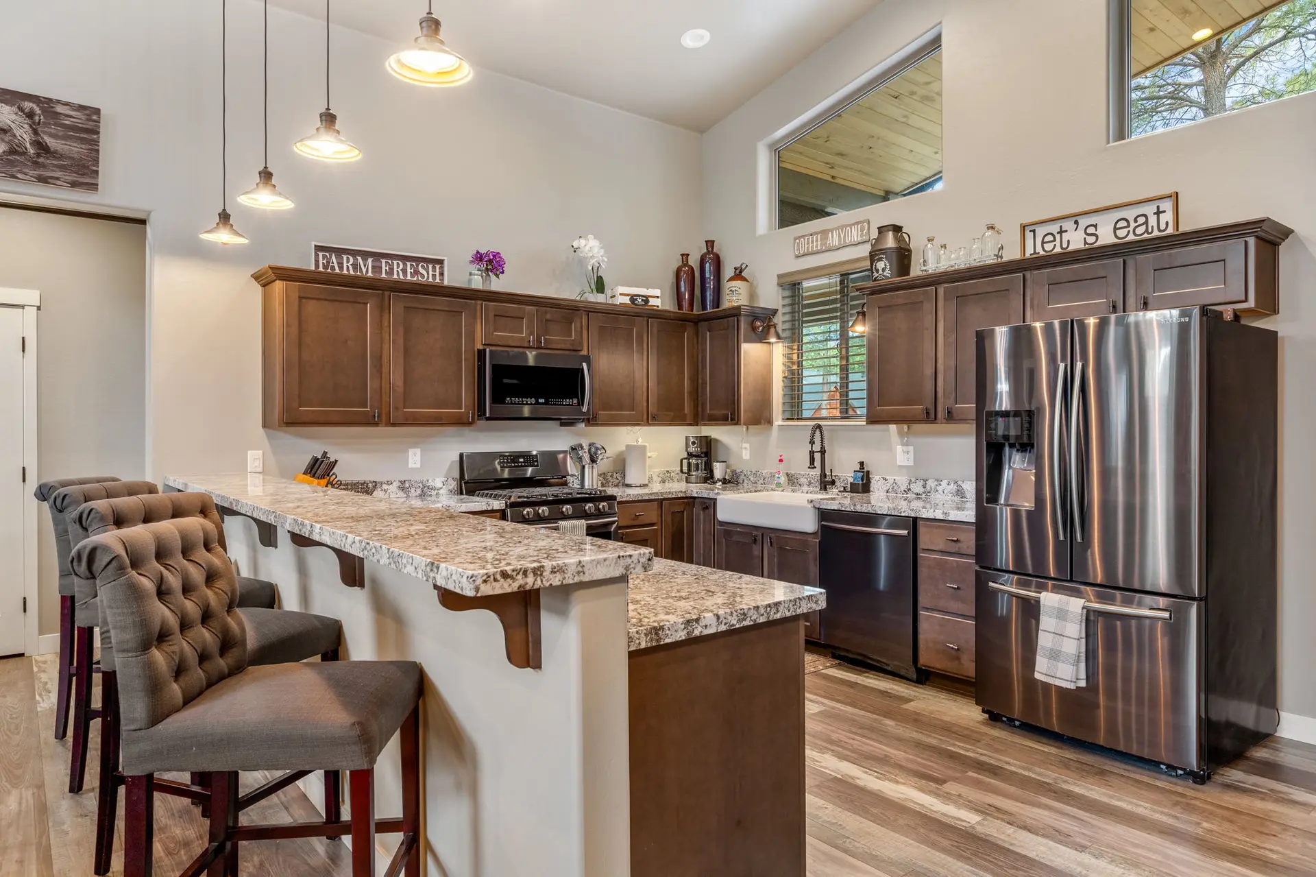 A kitchen with granite countertops, stainless steel appliances, and dark wood cabinets.