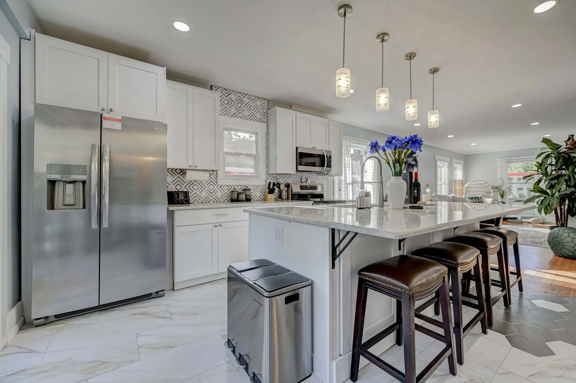 Modern kitchen with stainless steel refrigerator, white cabinets, granite countertops, and island wi