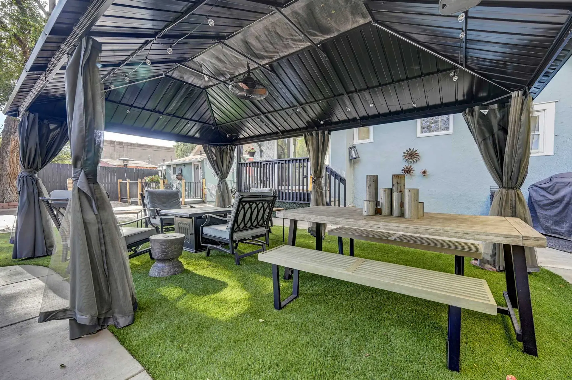 An outdoor gazebo with dining furniture and string lights.