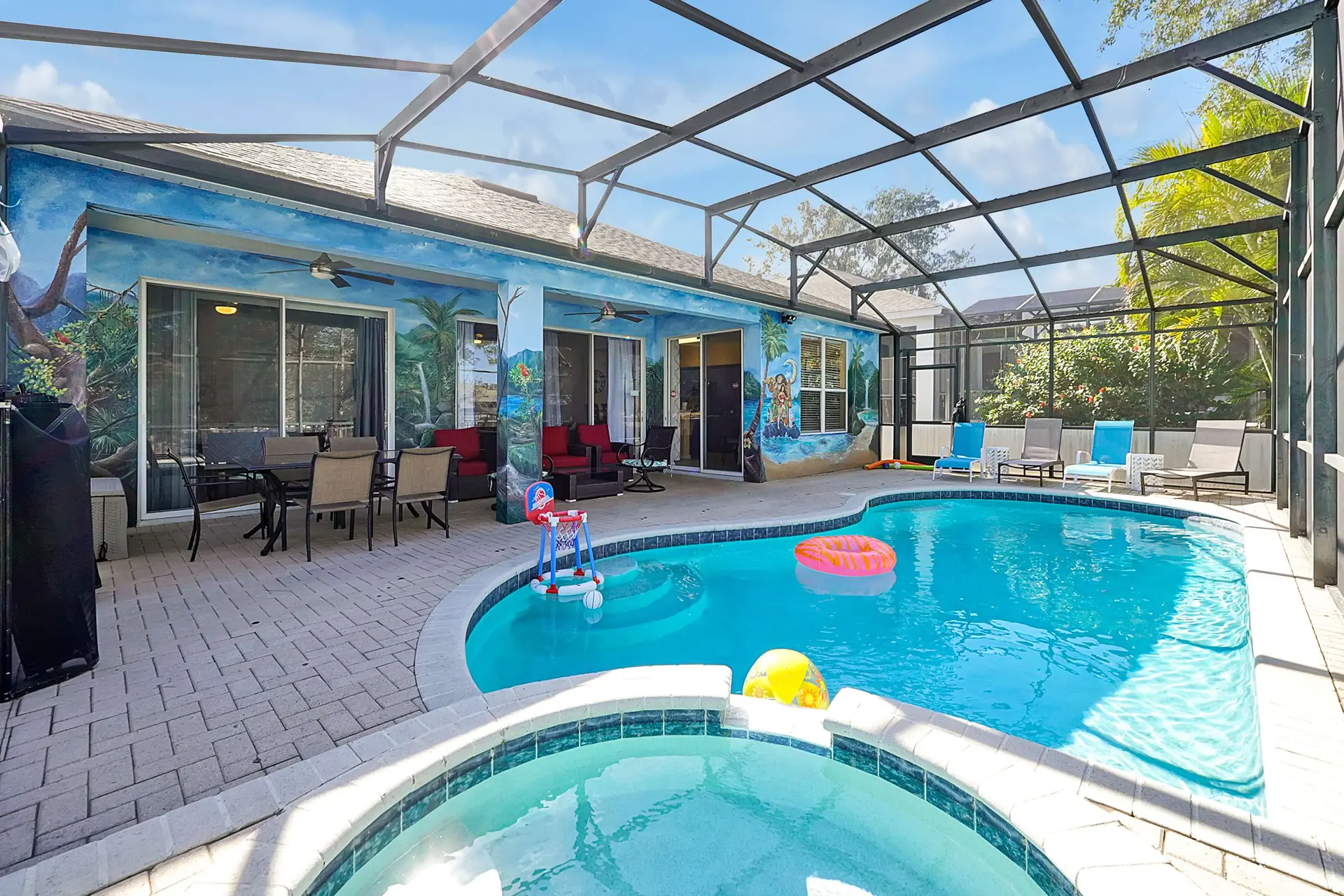 A screened-in backyard oasis with a pool, spa, lounge chairs, and a dining set.