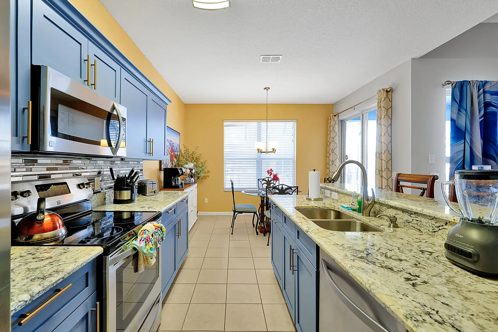 A modern kitchen with blue cabinets, granite countertops, and stainless steel appliances.