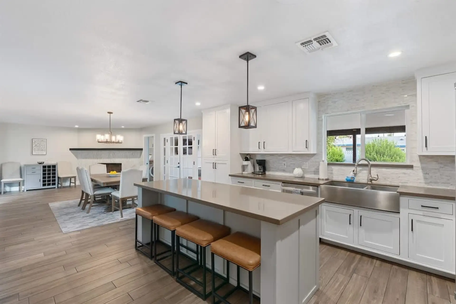 Modern kitchen with island seating, white cabinets, and stainless steel sink.