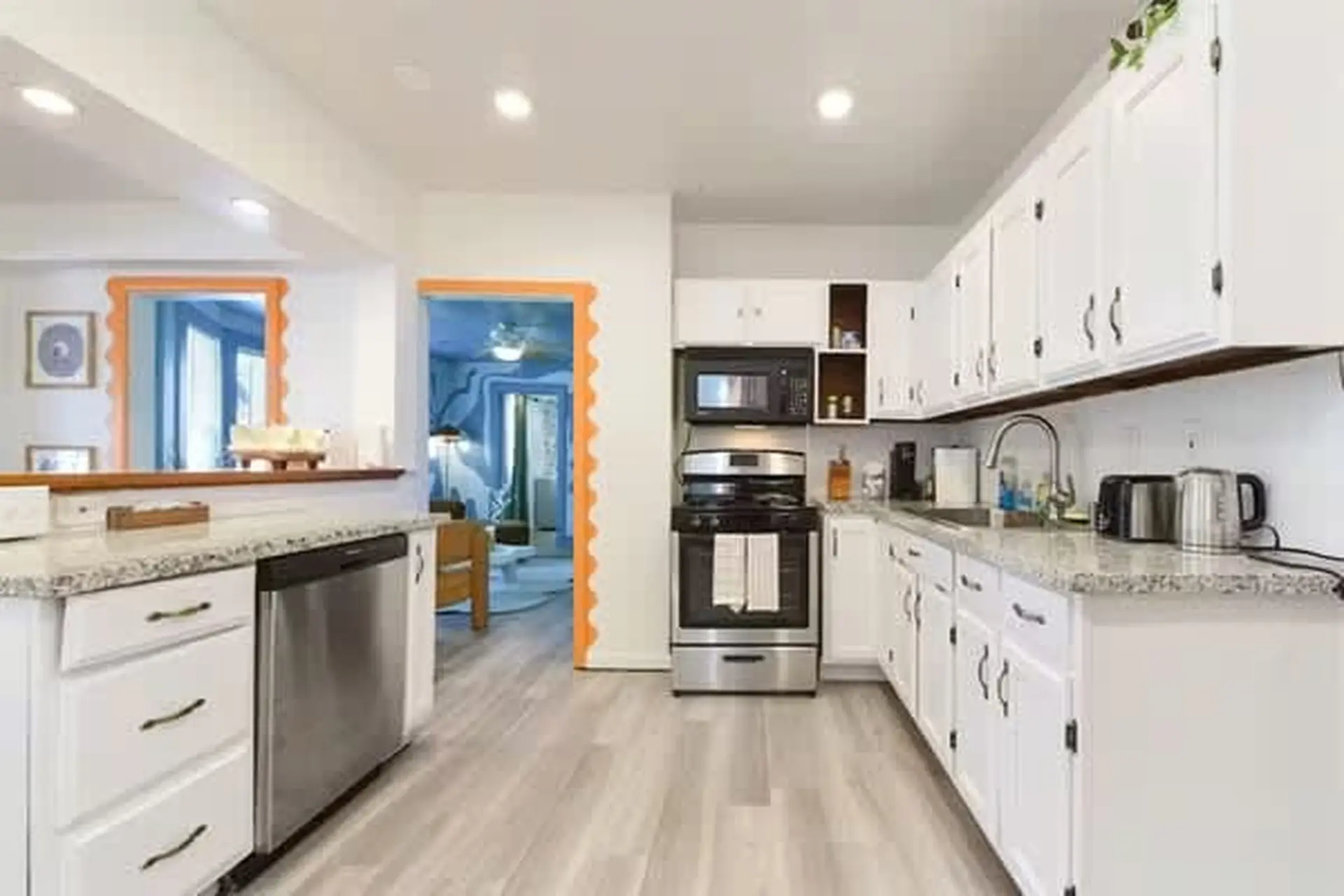 A modern kitchen with white cabinets, stainless steel appliances, and a gray granite countertop.