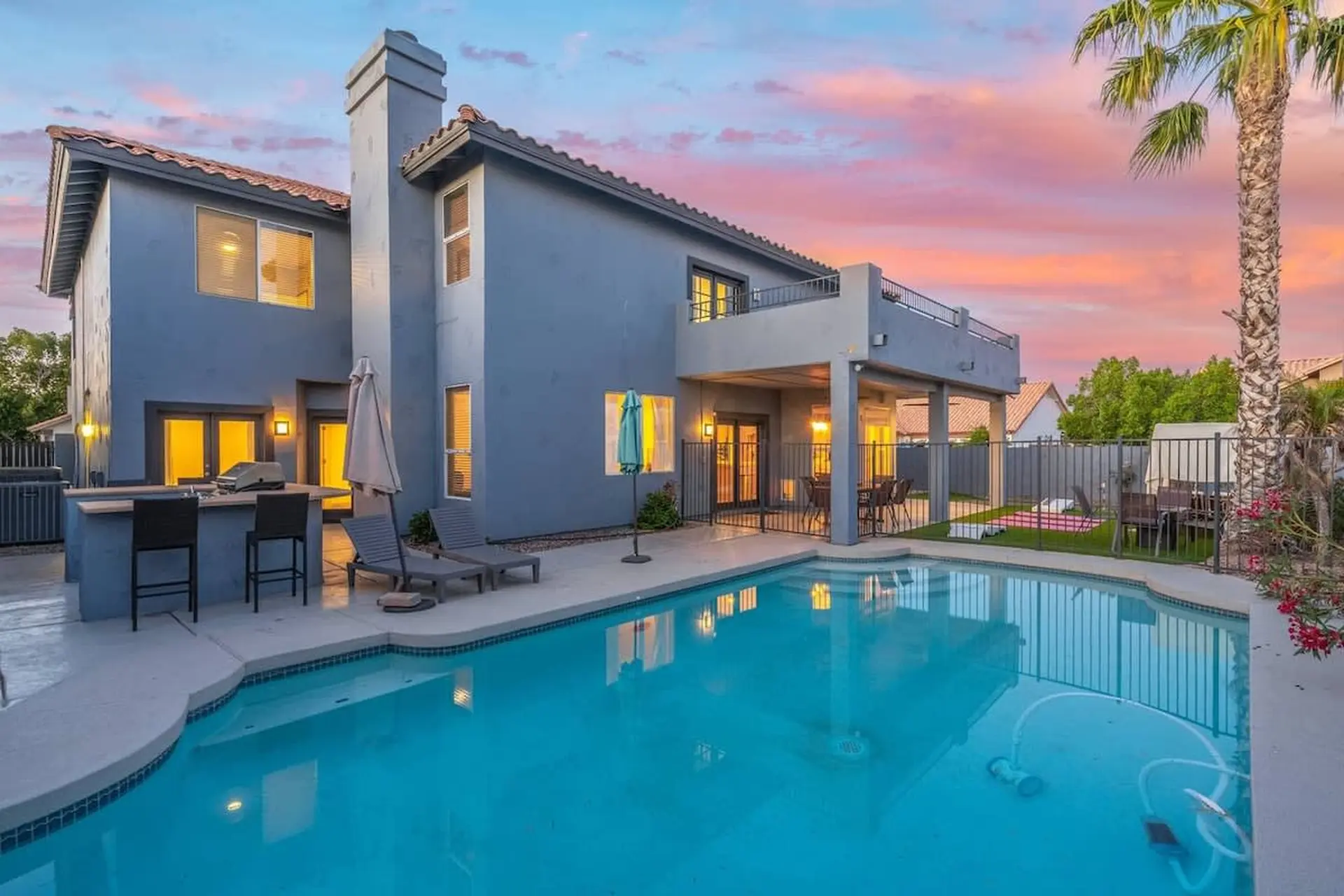A backyard oasis with a pool and palm tree at sunset.