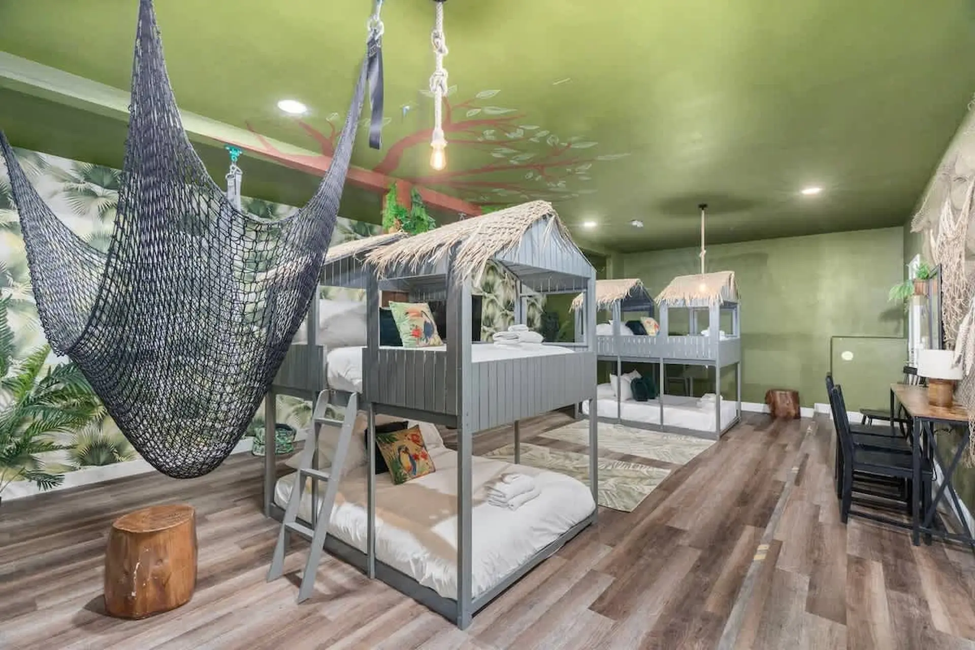 A jungle-themed bedroom with bunk beds and a hanging net chair.