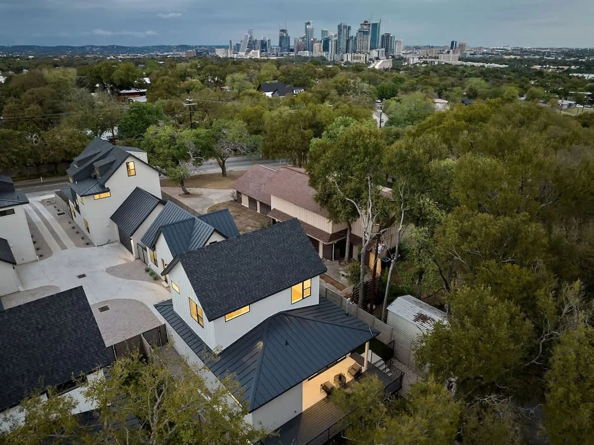 Aerial view of modern homes with dark roofs and a city skyline in the distance.