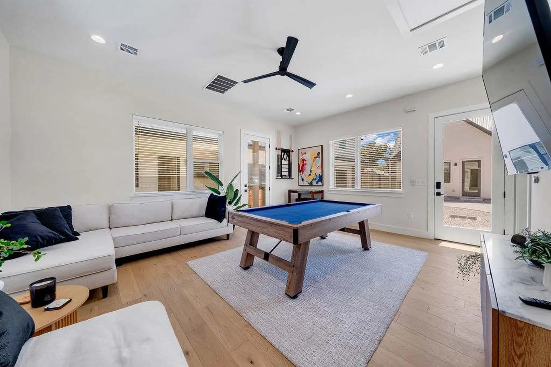 A modern living room with a pool table and sectional sofa.