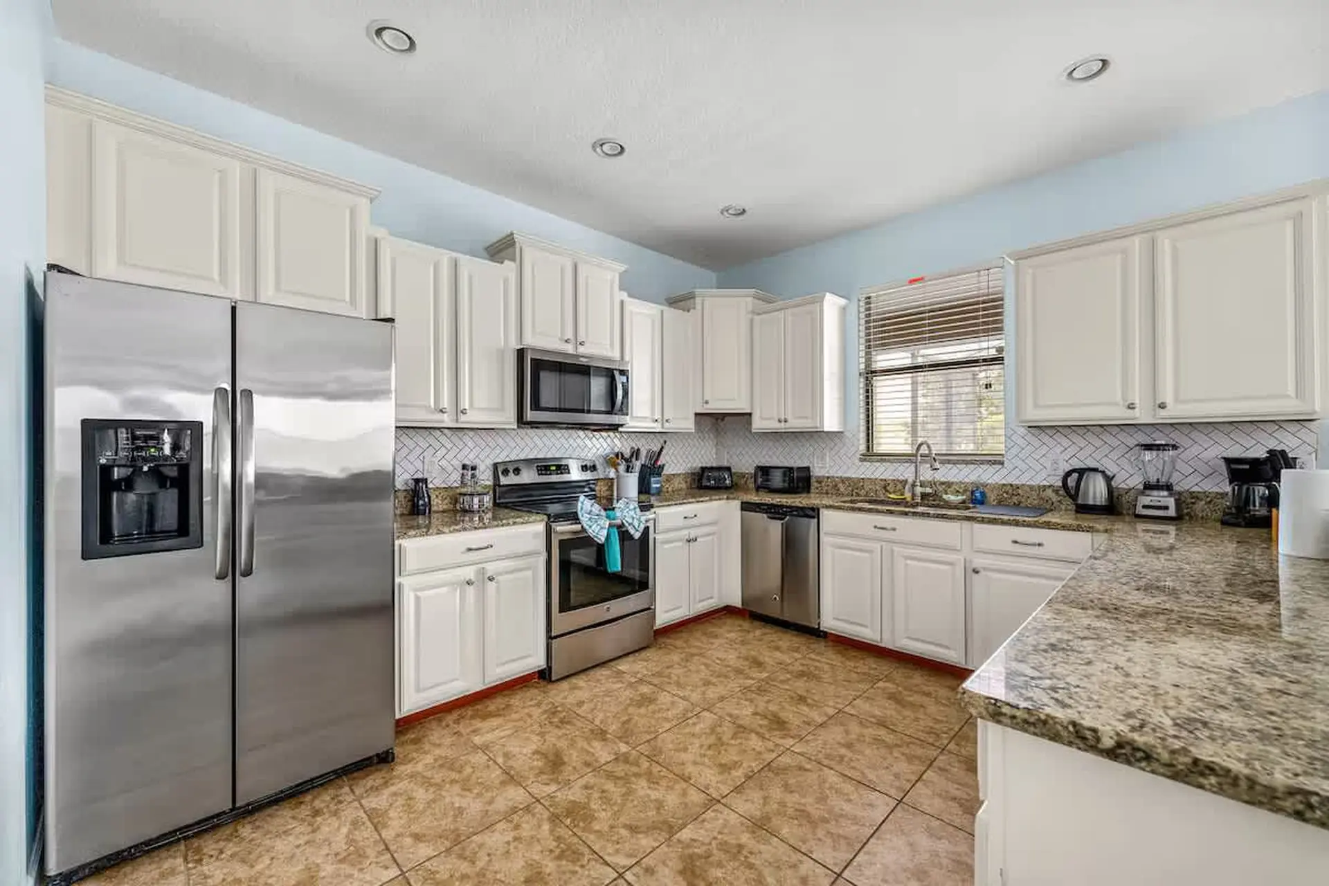 Kitchen with white cabinets, stainless steel refrigerator, oven, and dishwasher.