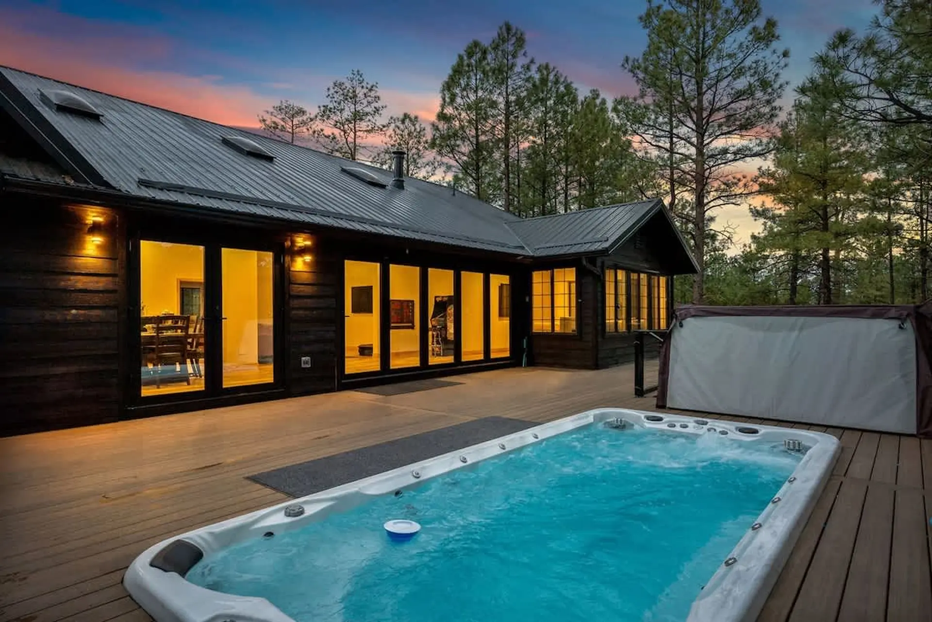 Luxury cabin with a hot tub on a wooden deck at twilight.