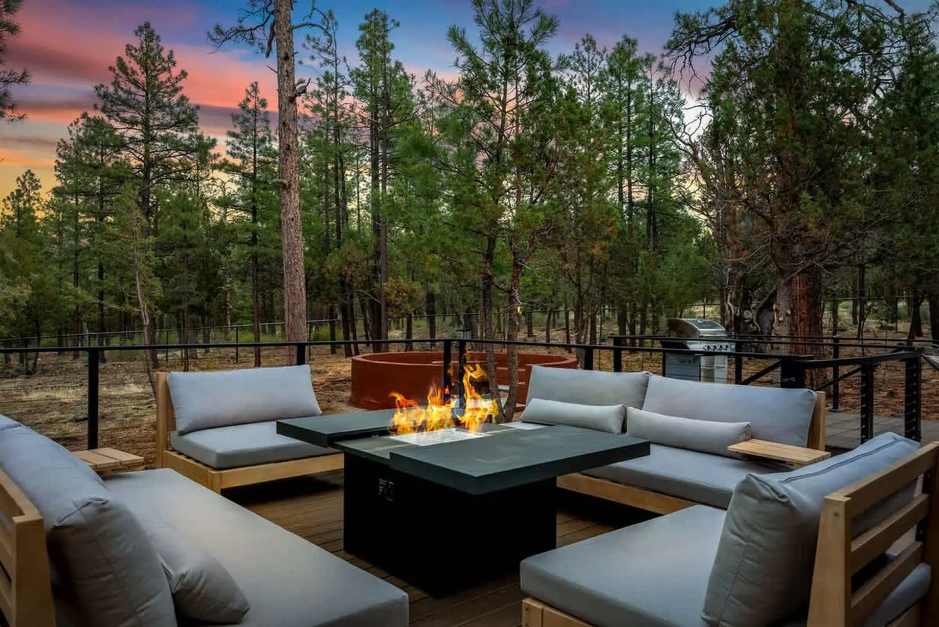 An outdoor patio area with fire pit and seating surrounded by trees.