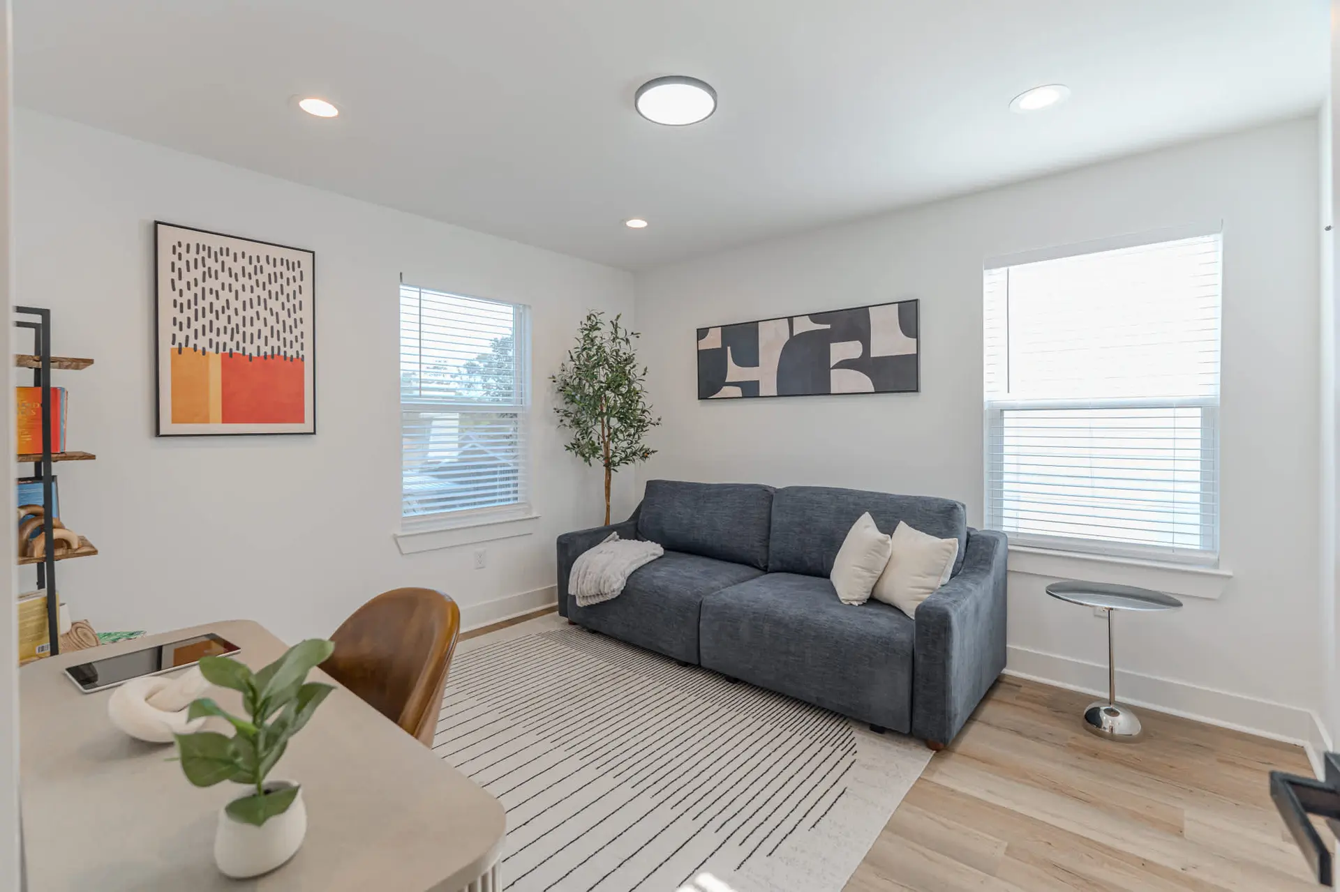 A cozy living room with a blue sofa, patterned rug, and modern art.