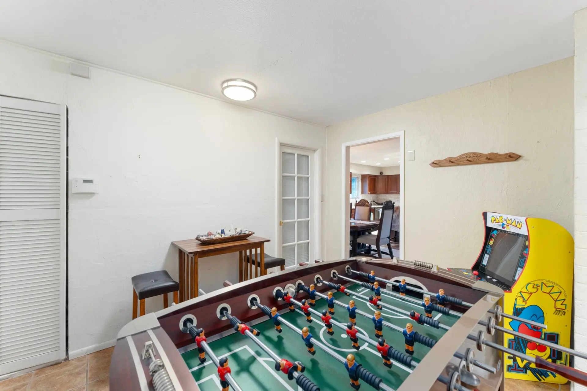 A game room with a foosball table and a Pac-Man arcade game.