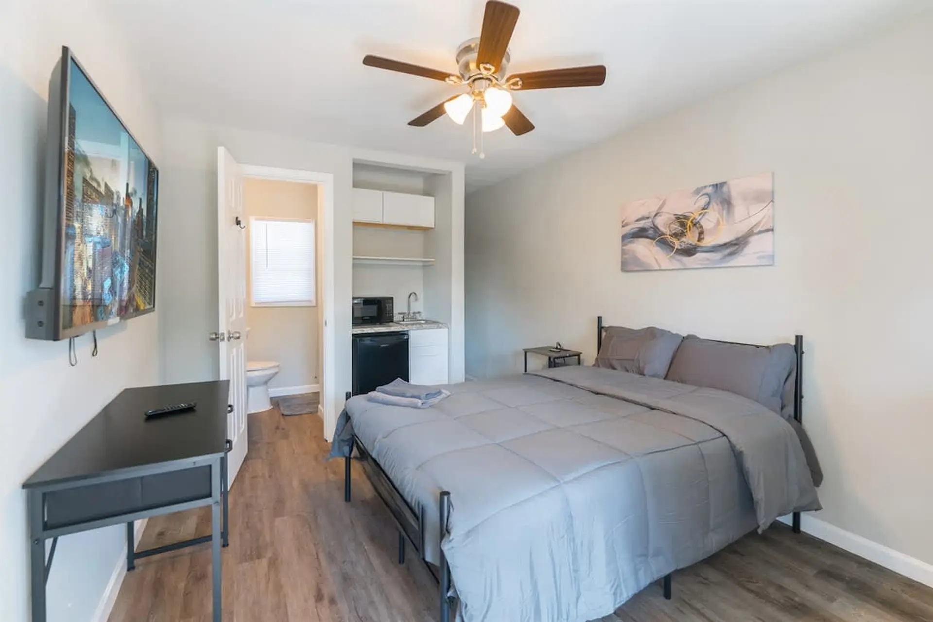 A bedroom with a large bed, a desk, and a TV.