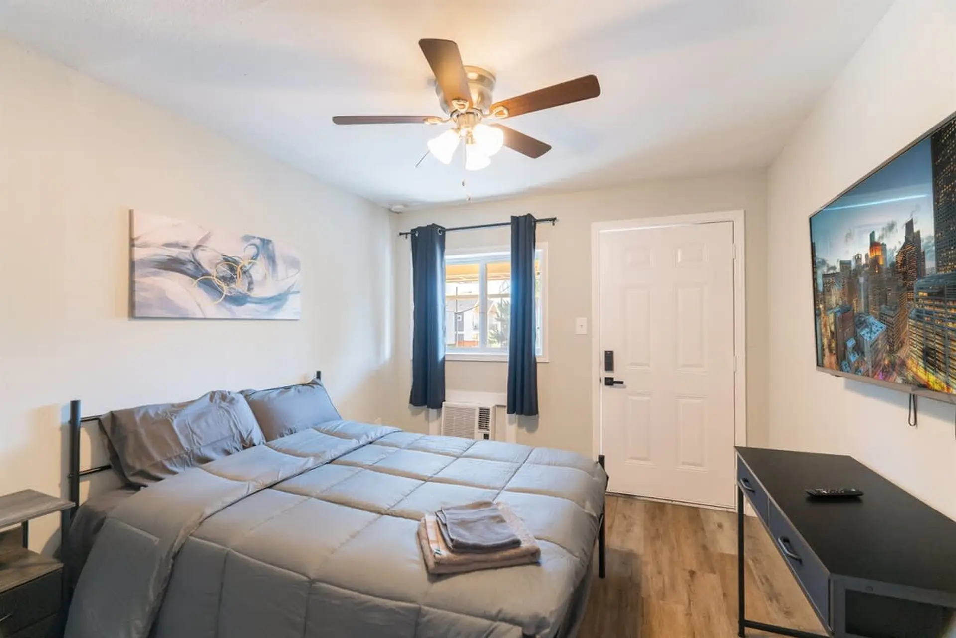 A bedroom with a bed, TV, window, and door.