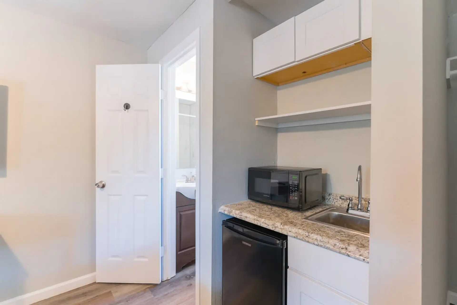 A bright white door is open to a bathroom, revealing a vanity.