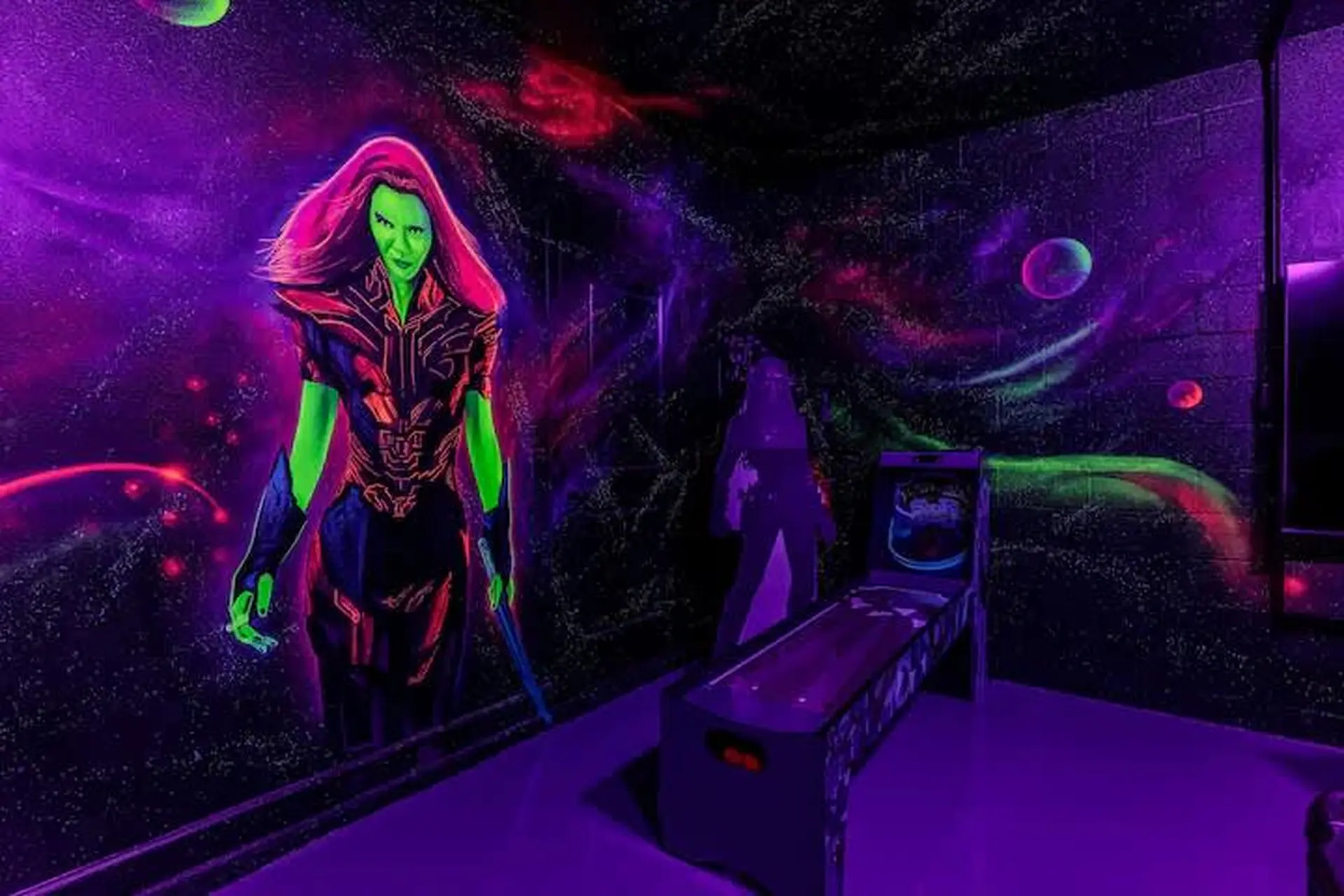 A neon purple room with a Gamora mural and a Skee-Ball machine.