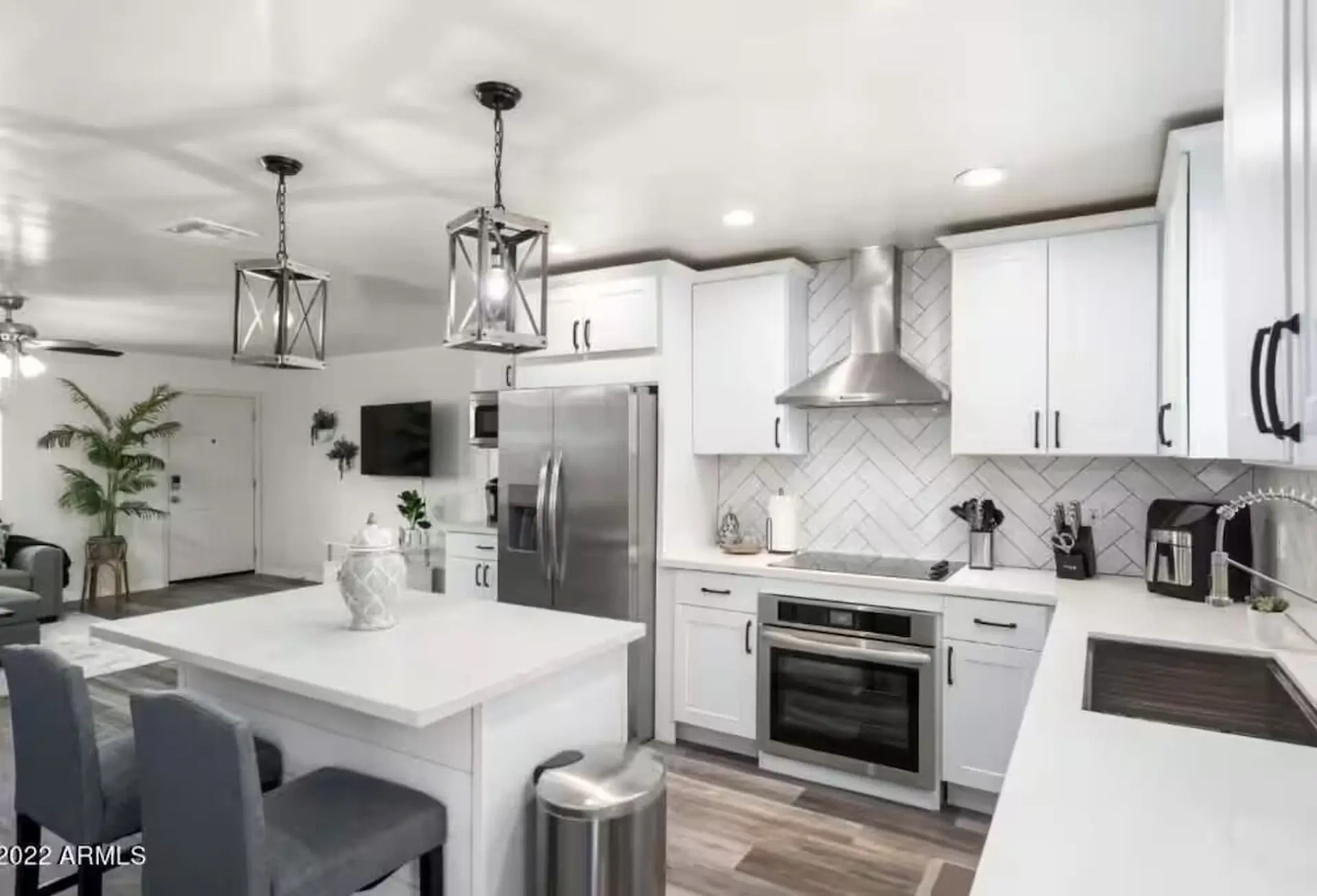 Modern kitchen with white cabinets, stainless steel appliances, and a large island.
