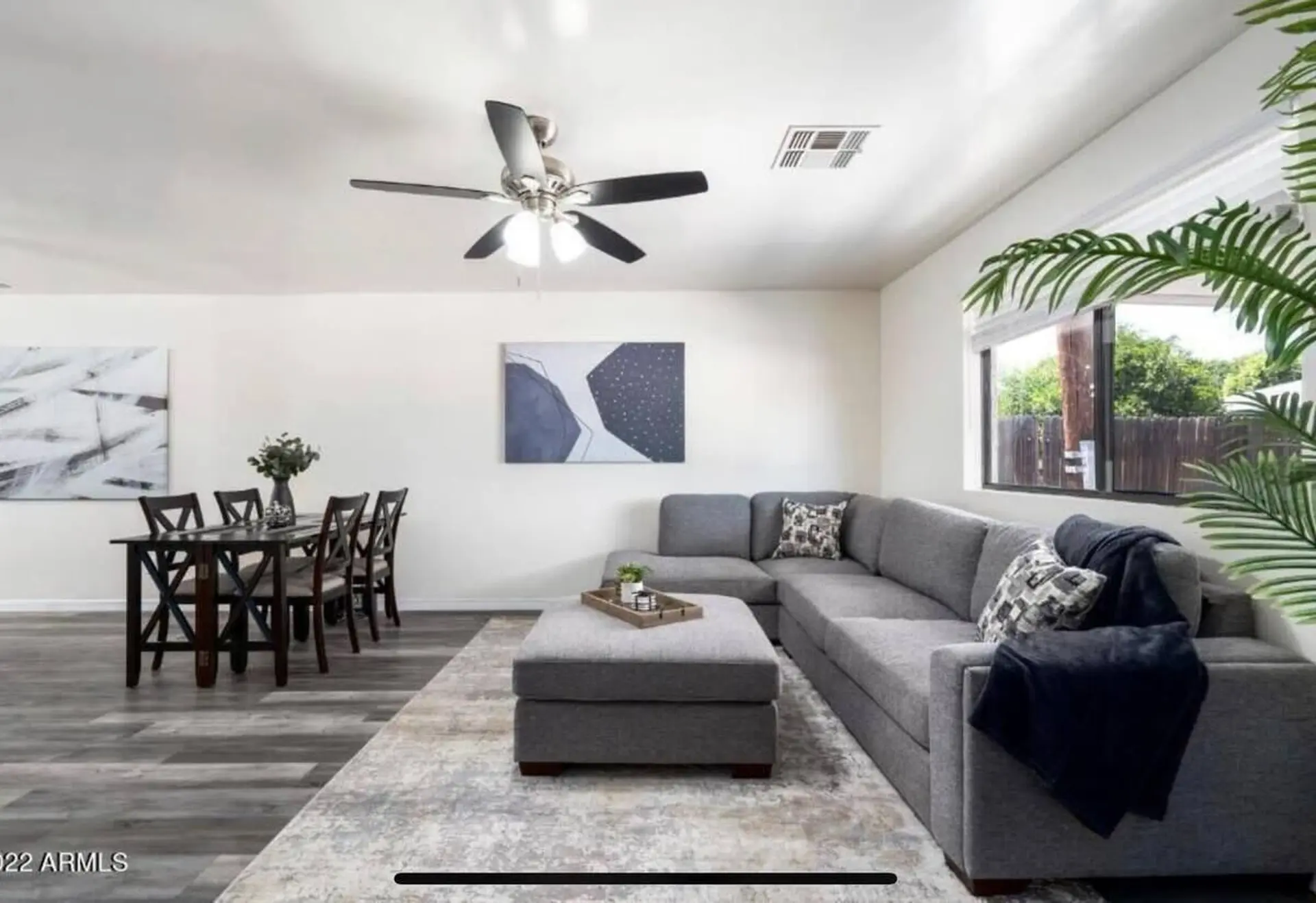 A sectional sofa and ottoman sit on a patterned rug in a living room.