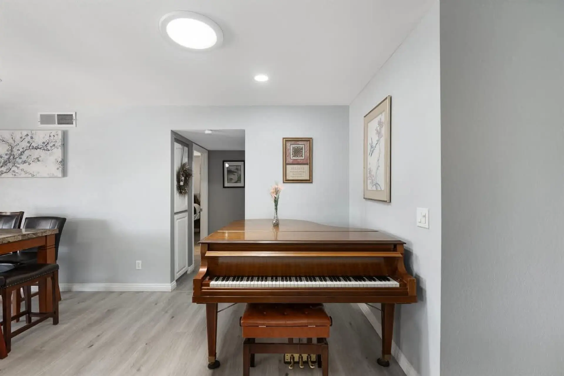 A grand piano with a wooden bench sits in a room with light blue walls.