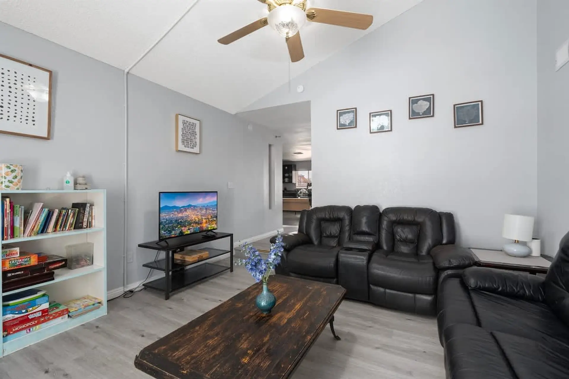 A living room with a black leather couch and a flat-screen TV.