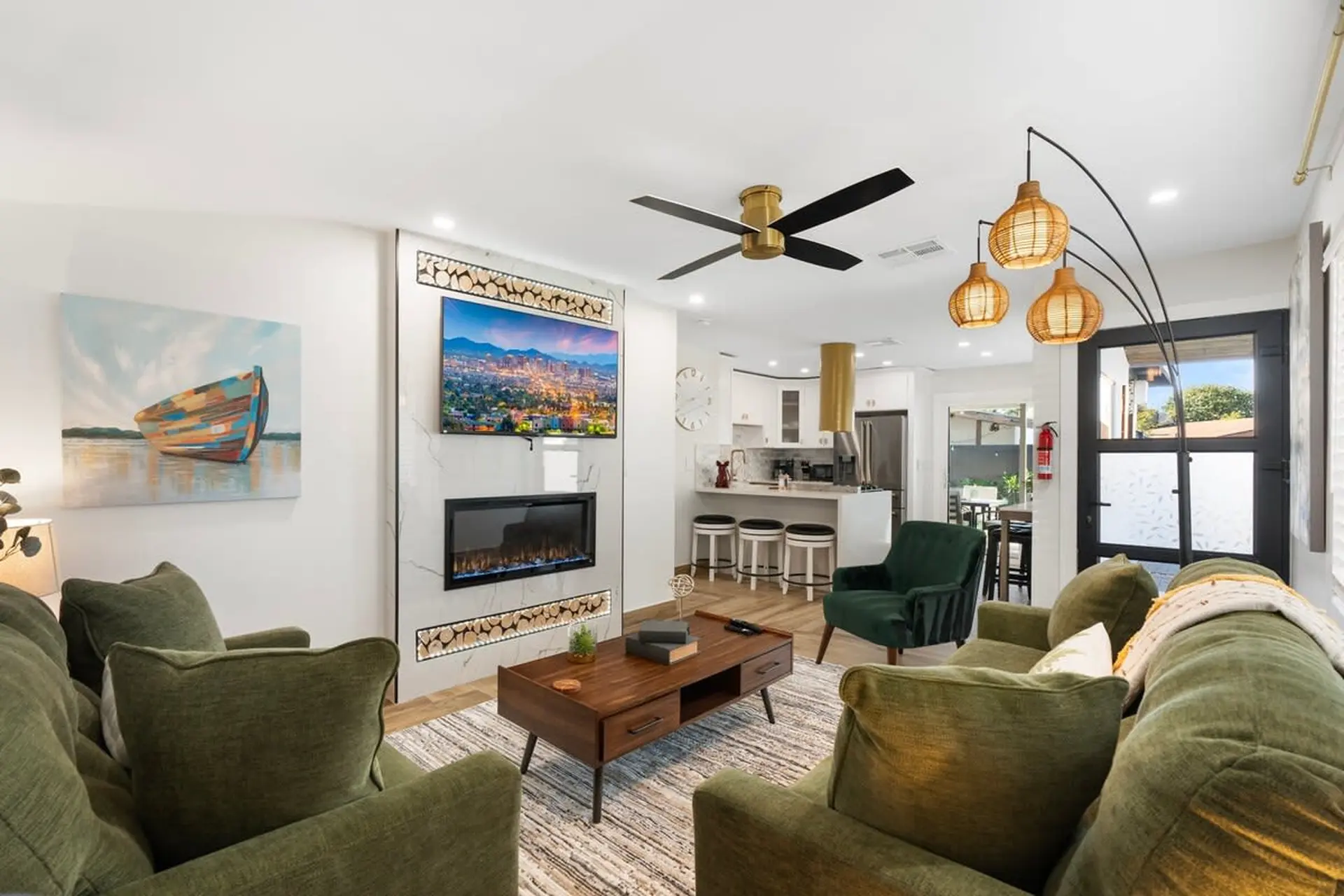 A living room with green couches, a fireplace, and a cityscape painting.