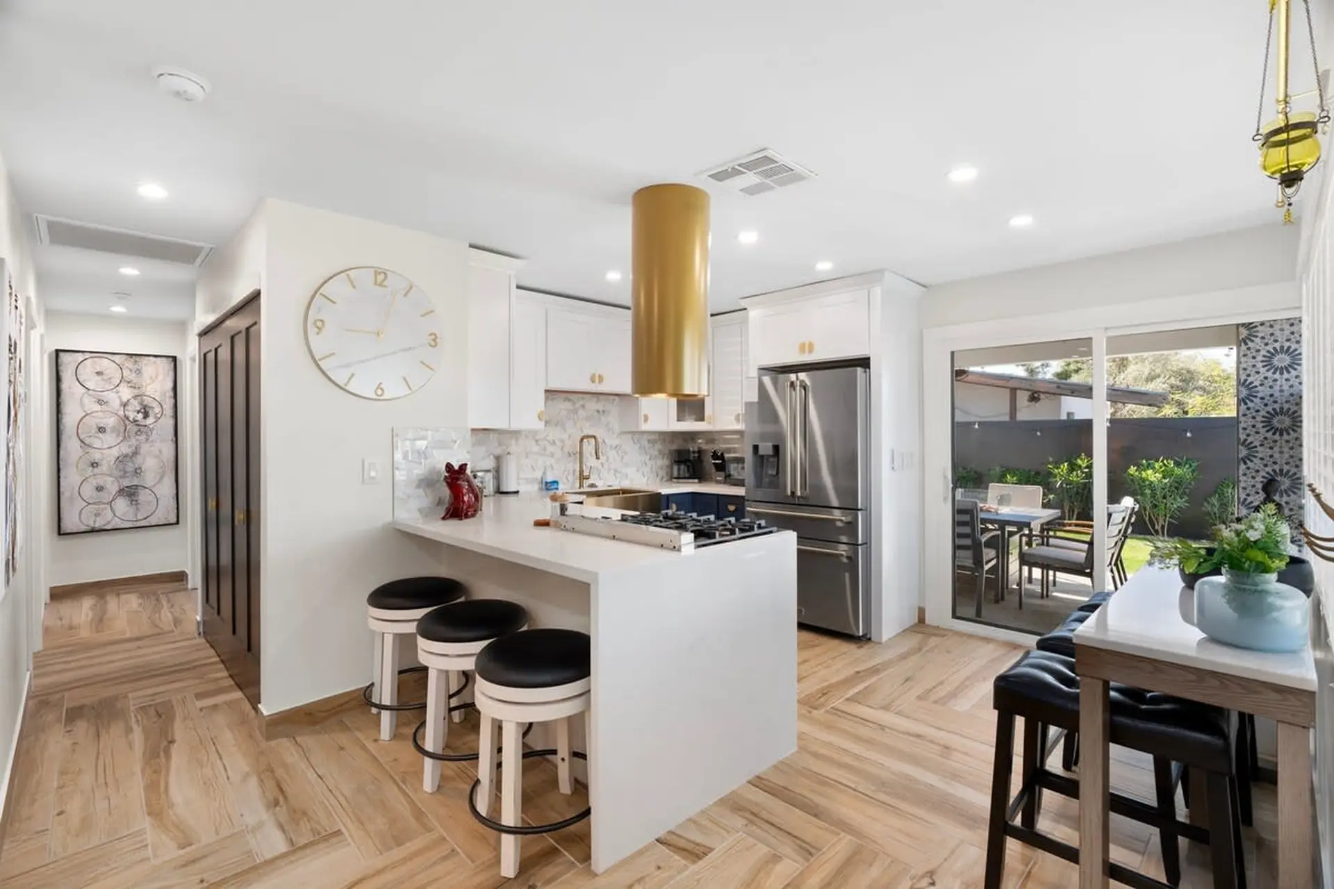 A modern kitchen with white cabinets, a gold range hood, and stainless steel appliances.