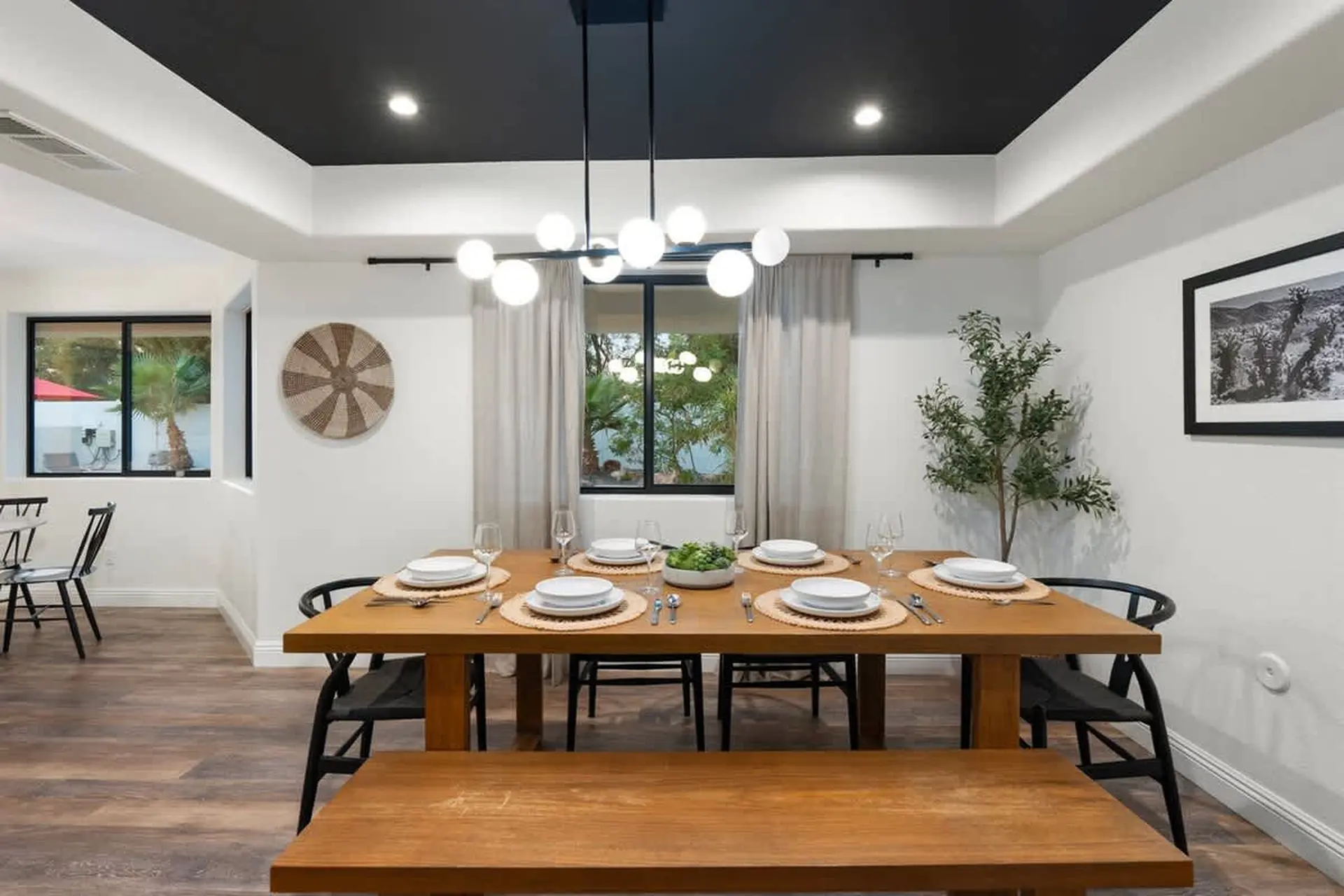 A dining room with a black ceiling, dining table, chairs, and bench.