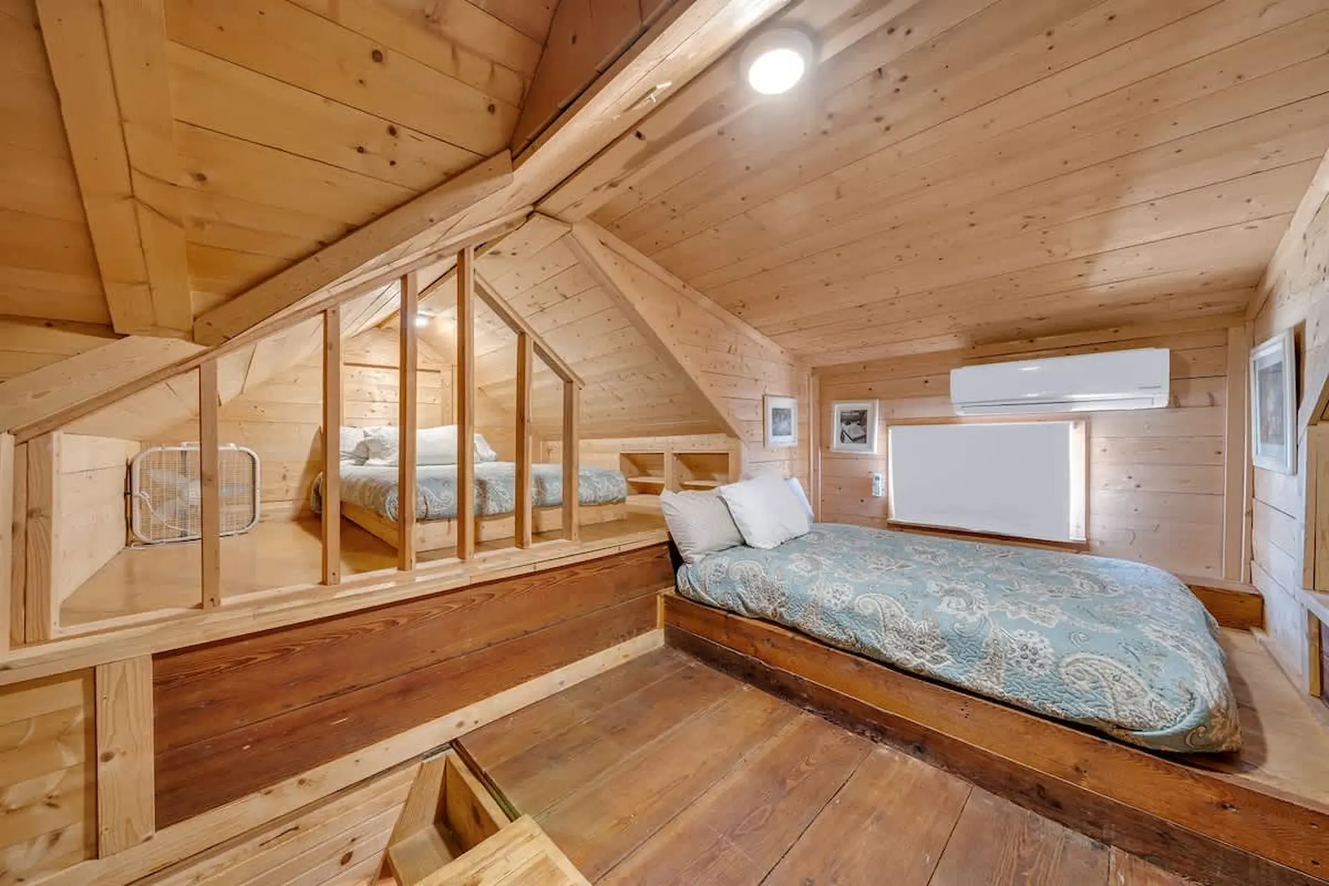 Loft bedroom with two beds, a fan, and an air conditioner.