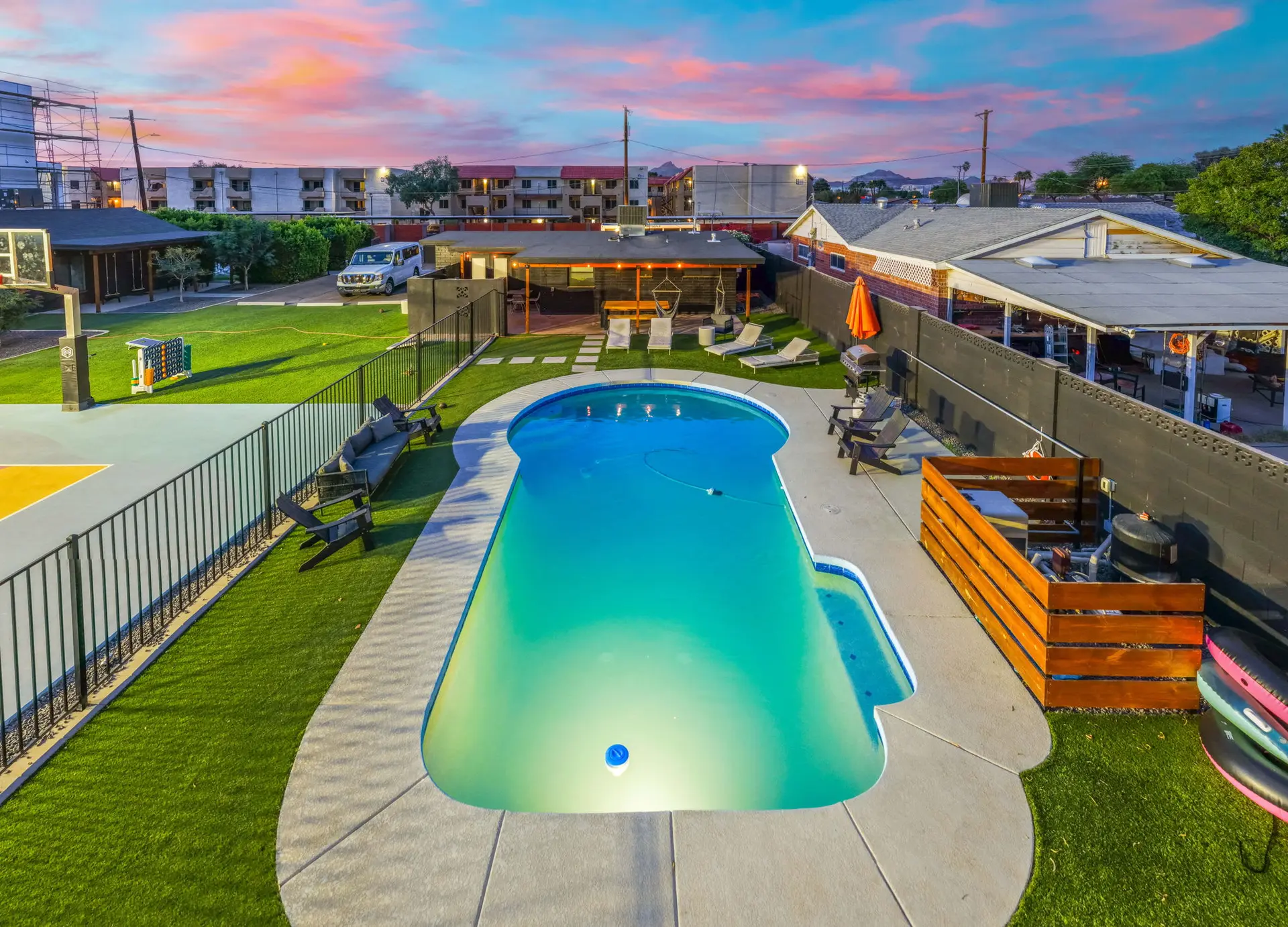 Backyard oasis with a kidney-shaped pool, basketball court, and lounge chairs.