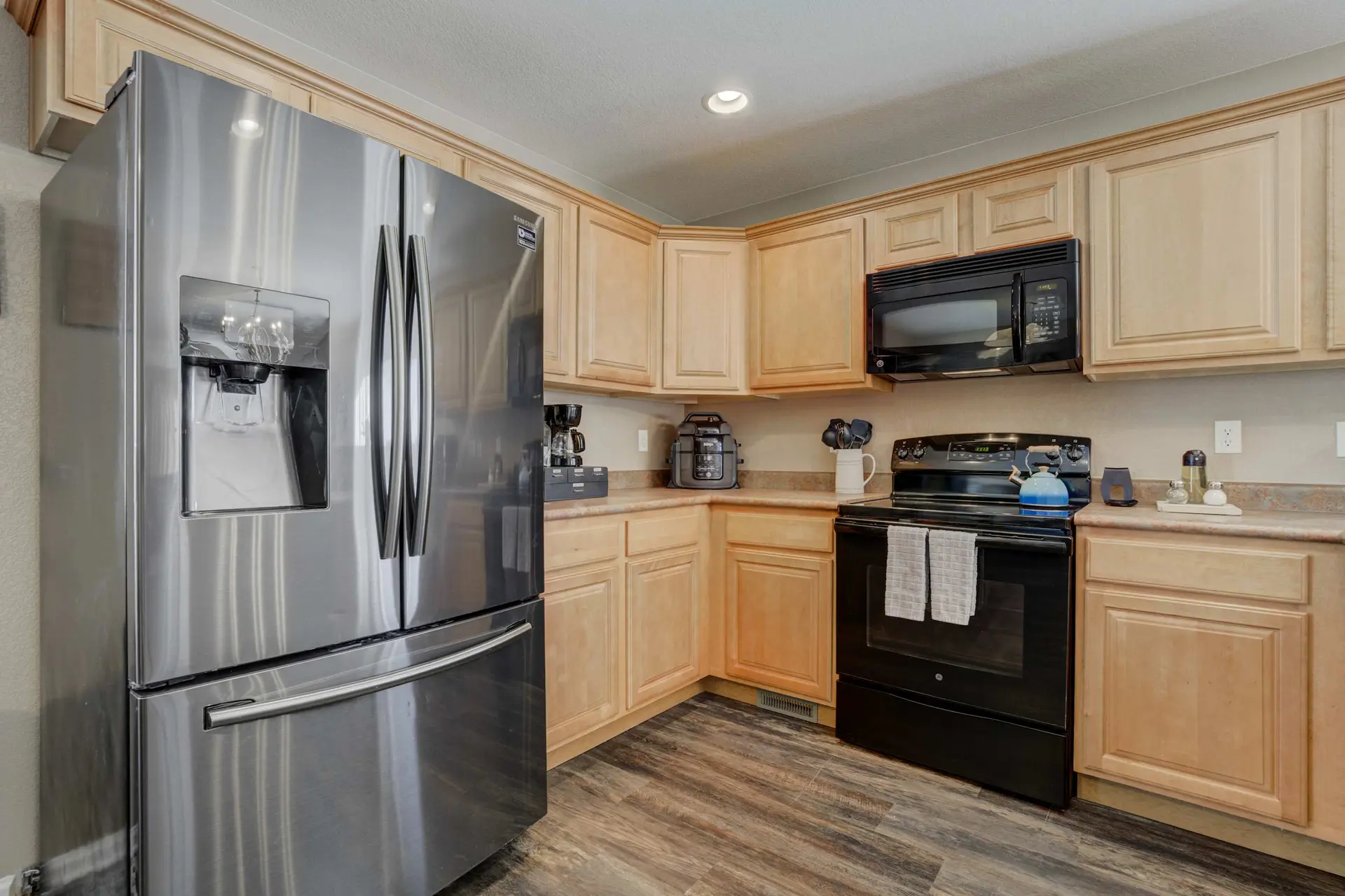 A kitchen with stainless steel appliances and light wood cabinets.